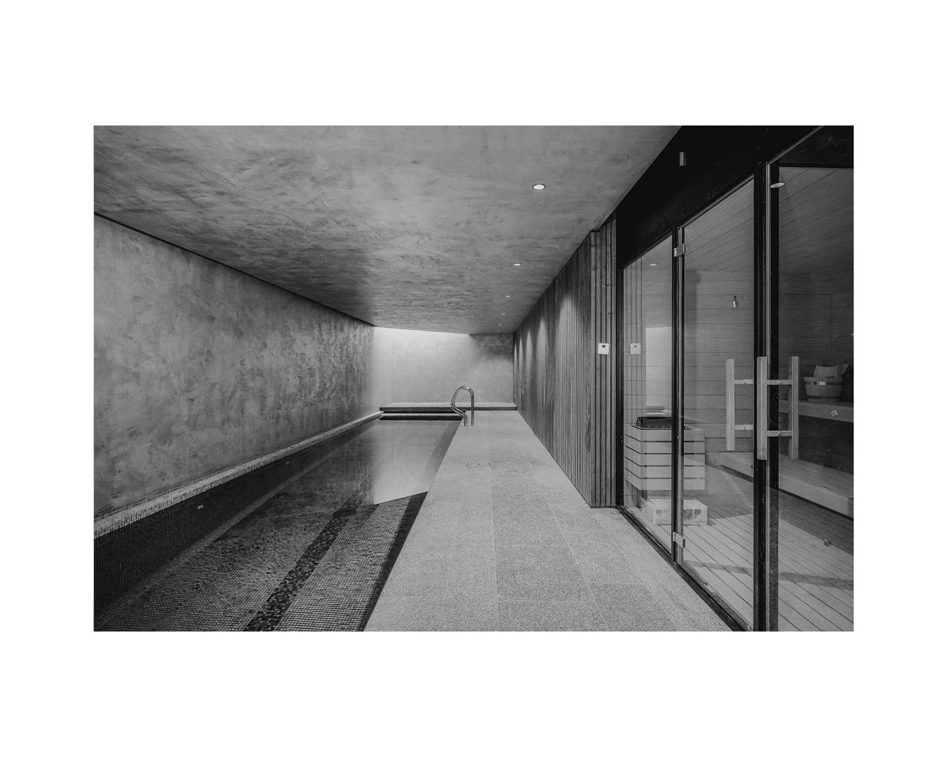 Contemporary concrete corridor with floor-to-ceiling windows overlooking an exterior view.