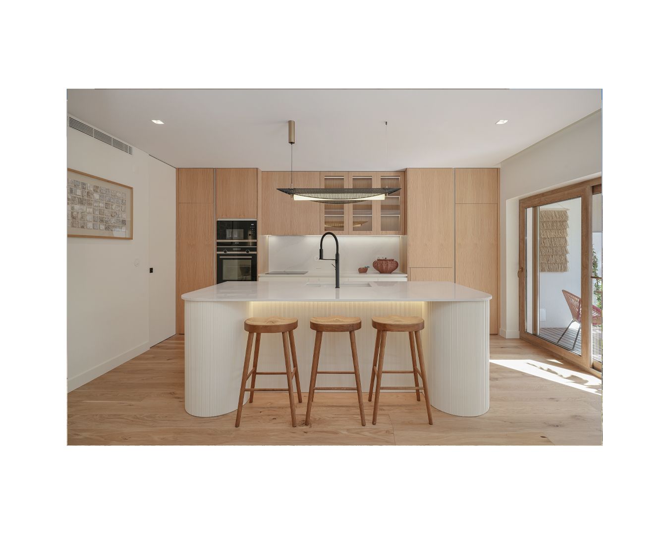 Sleek kitchen design with white curved counter and wooden bar stools in neutral tones.