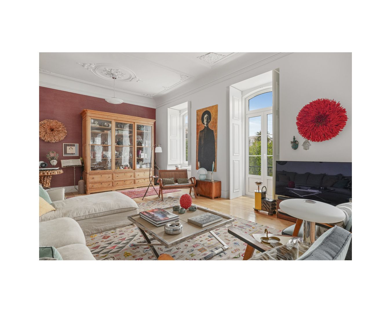 Luxurious living room with red accent wall, statement artwork, and elegant white seating arrangement.