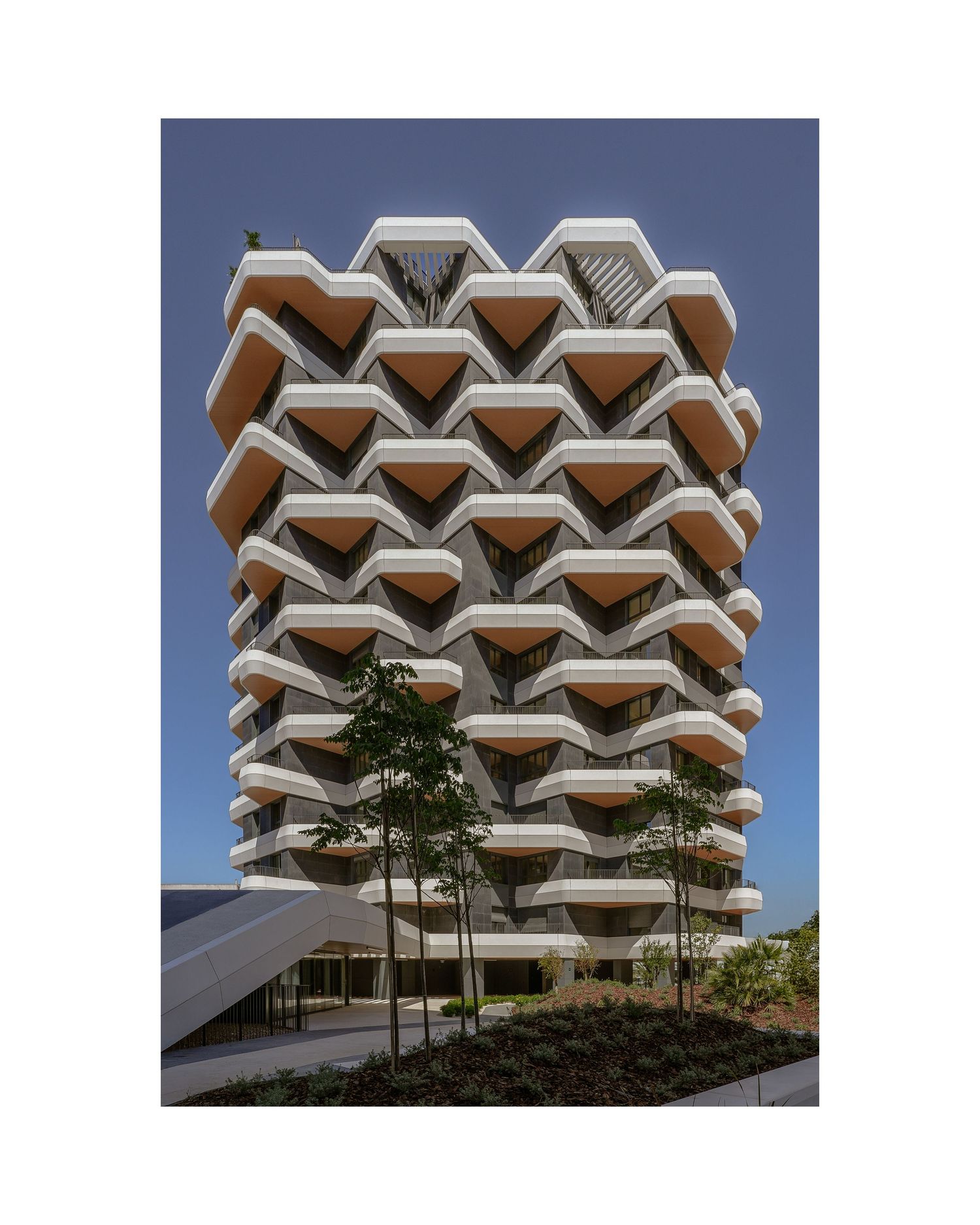 Striking modern apartment building with hexagonal balconies creating a honeycomb pattern against blue sky.
