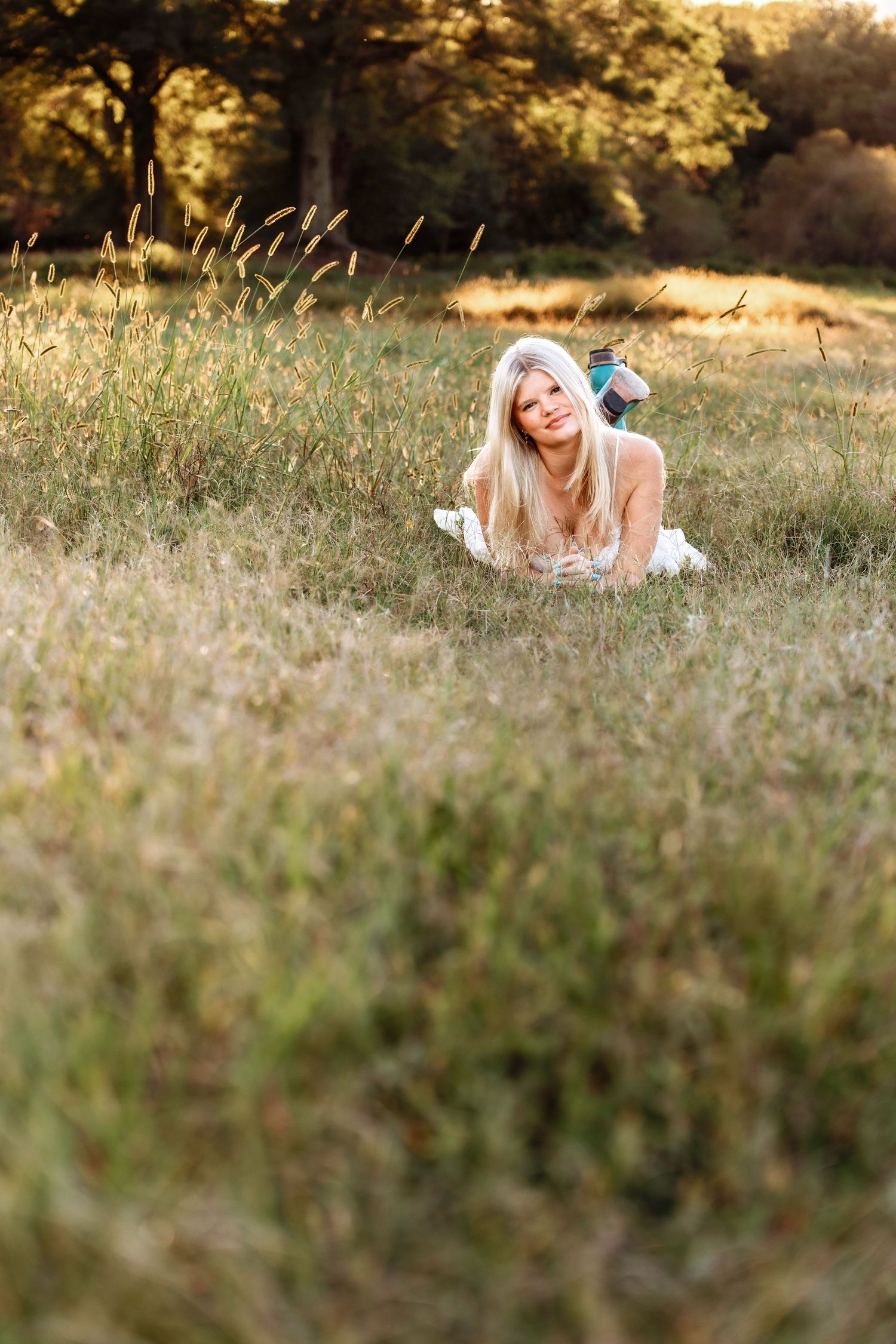 Artistic portrait through tall grass during golden hour in a natural field setting.
