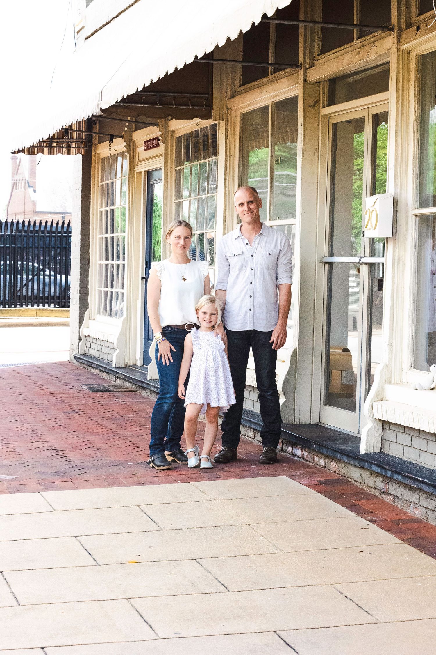 Family photos taken on covered porch of historic building with white pillars.