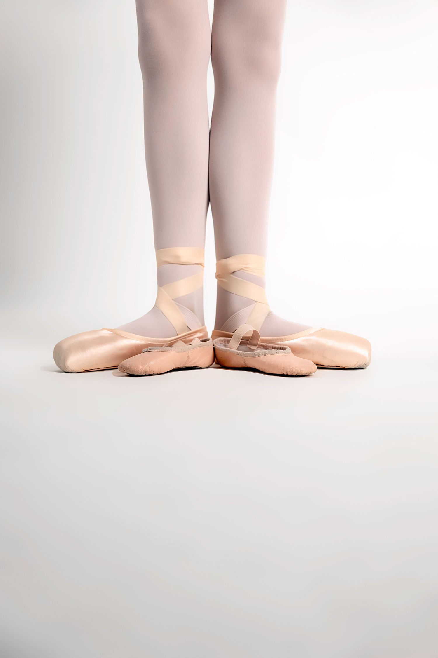 Close-up of ballet feet in pink tights and pointe shoes demonstrating positions.