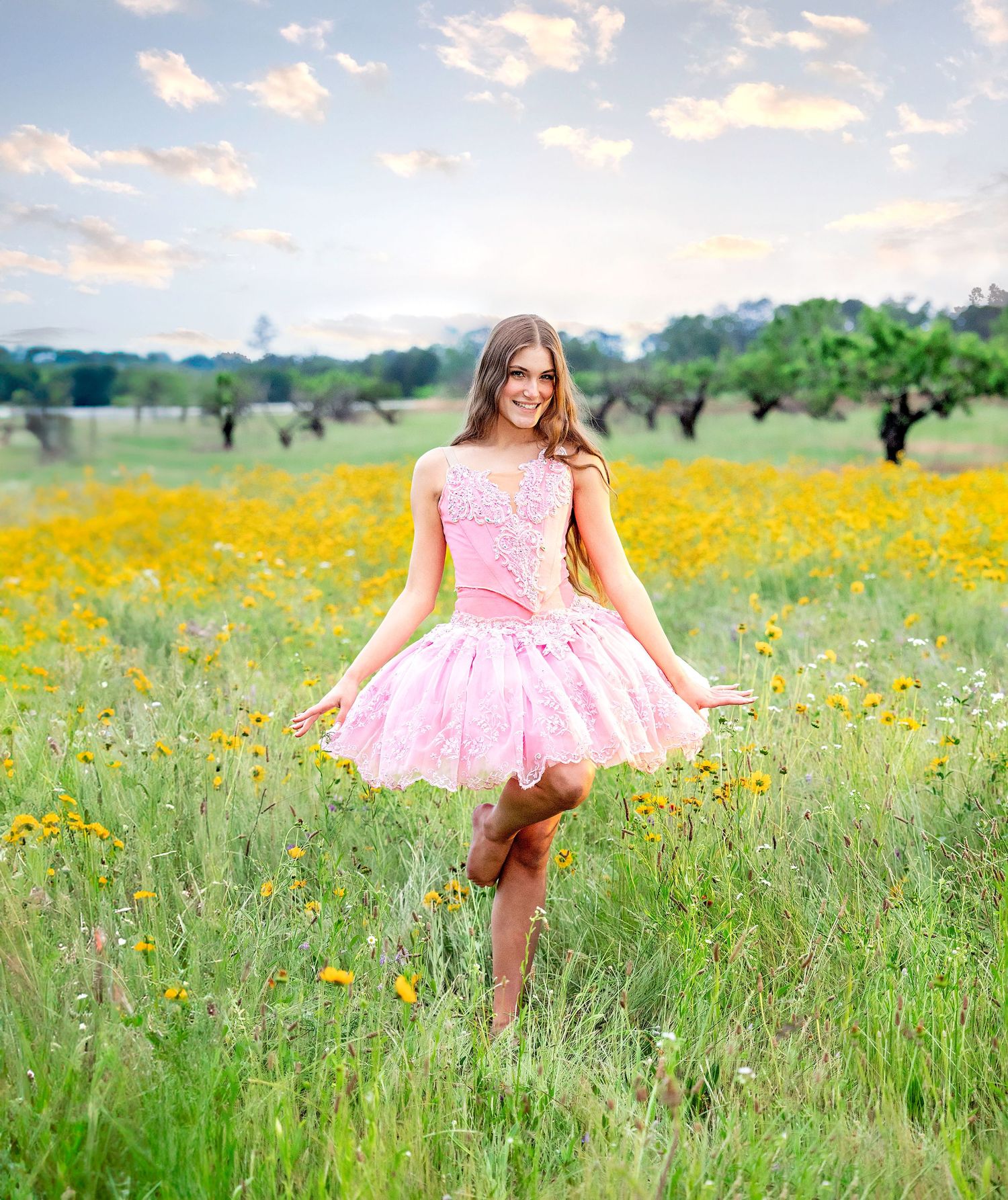 A person in a pink dress twirls joyfully through a vibrant meadow filled with yellow wildflowers and tall grass at sunset.