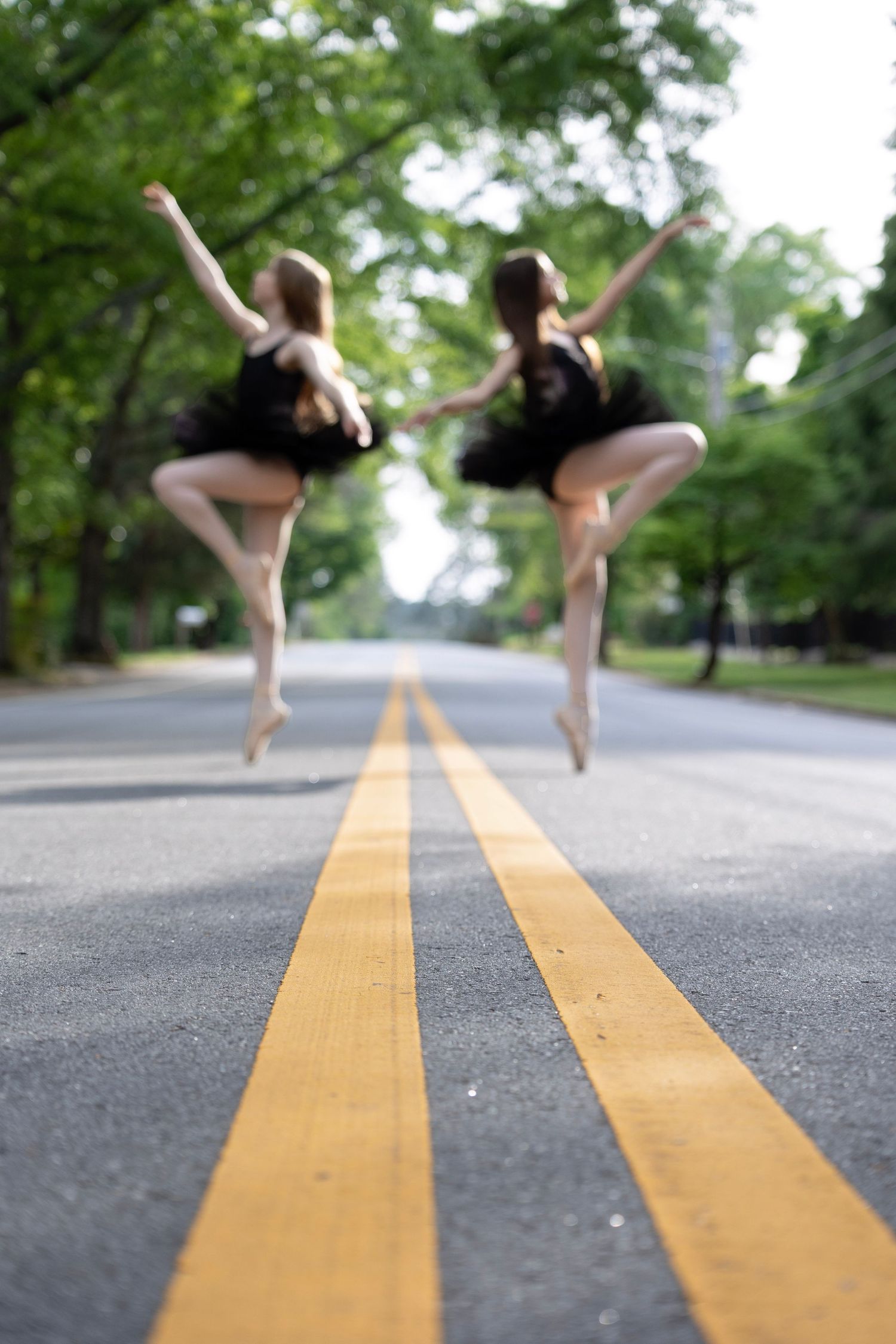 Artistic dance poses silhouetted against yellow road lines in street photography series.