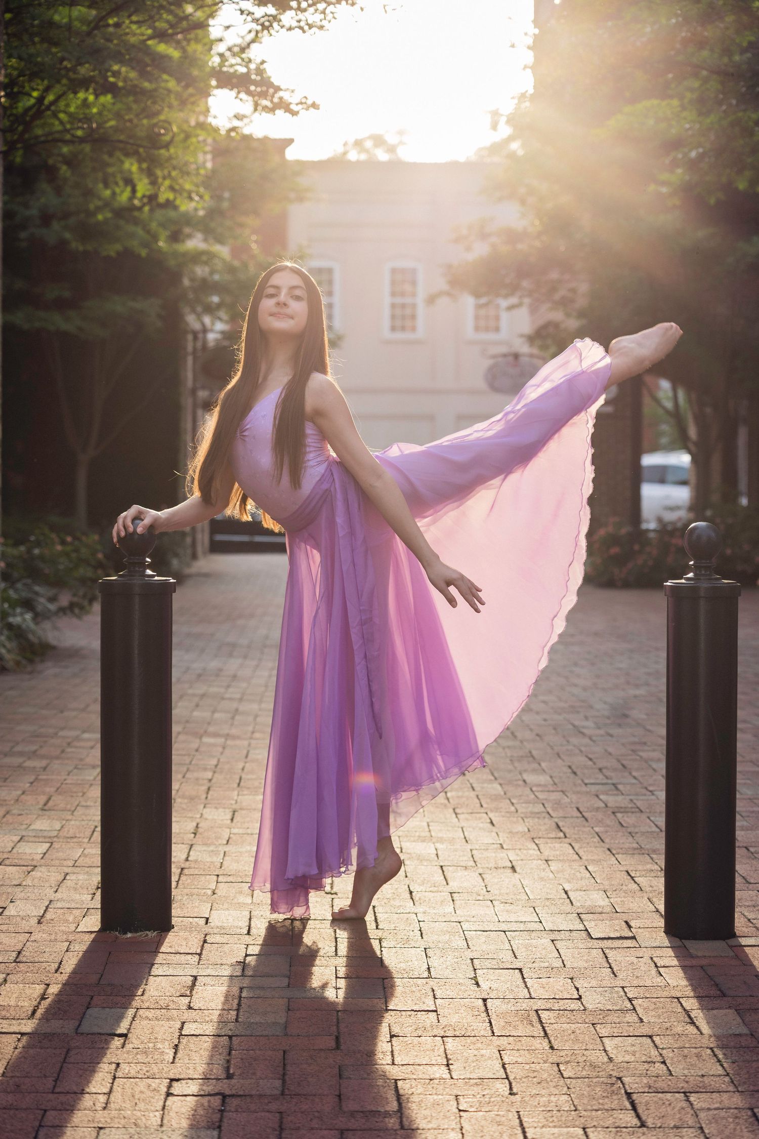 Ethereal portraits with flowing purple dress captured at sunset on brick courtyard.