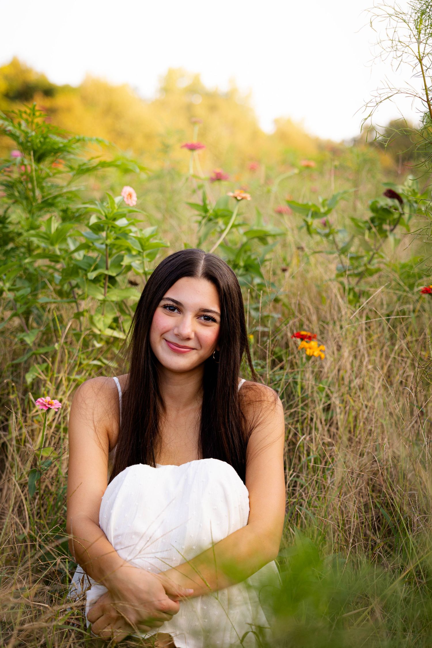 Woman in white dress posing in a wildflower field during golden hour.