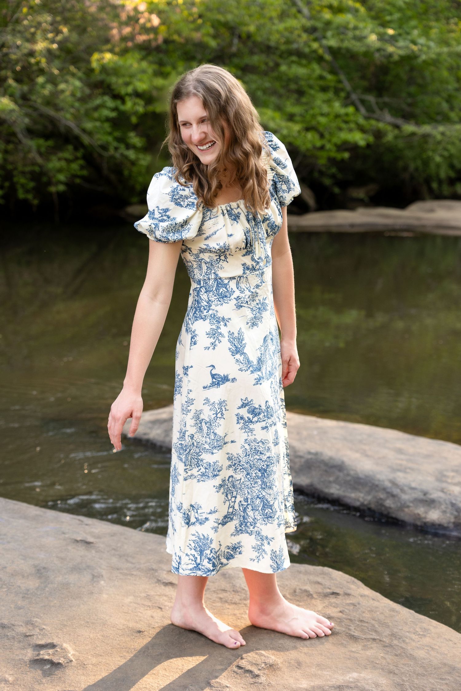 Blue and white floral dress portrait by creek with natural water backdrop.