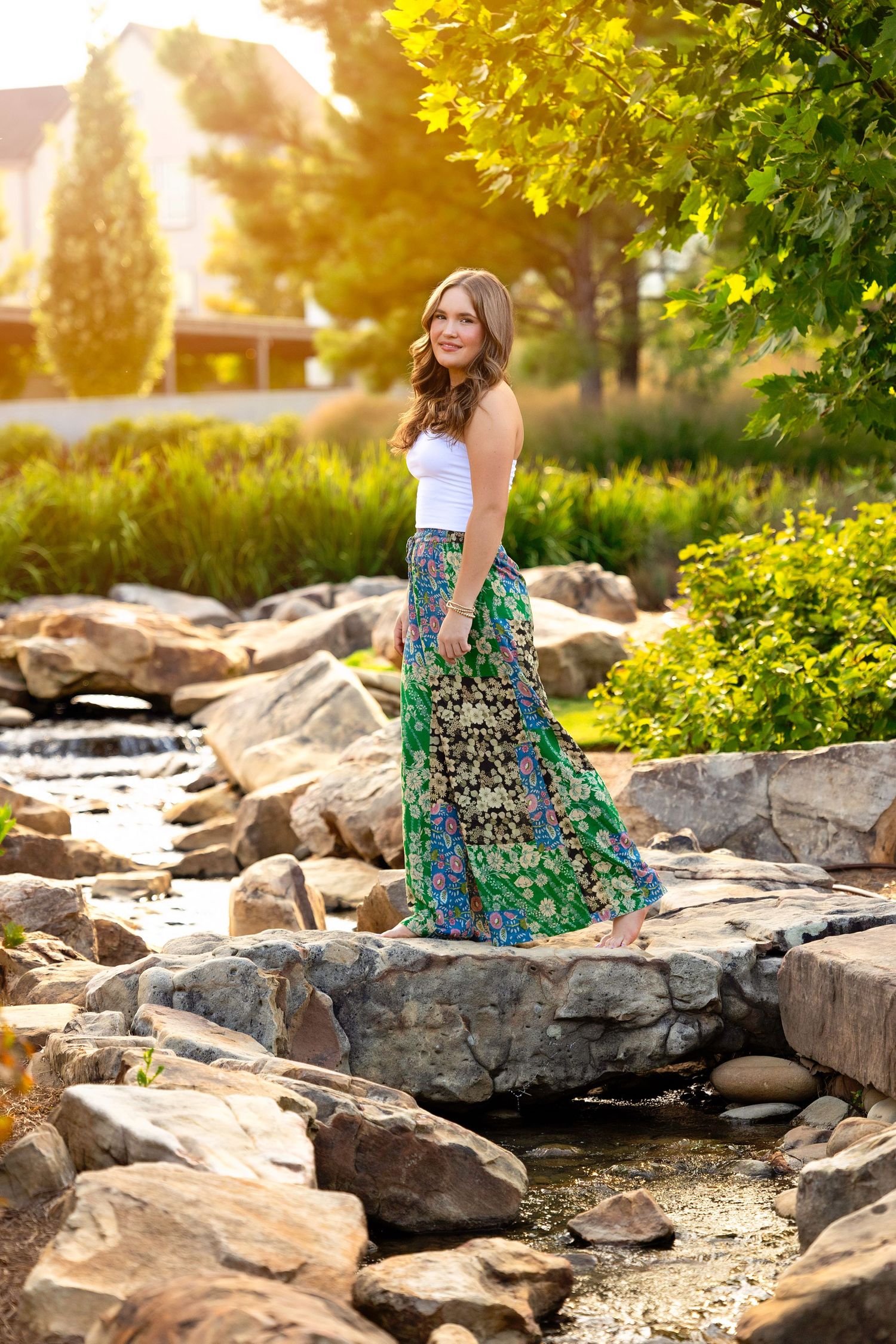 A colorful floral dress stands out against rocky terrain and golden sunlight in a scenic outdoor setting.