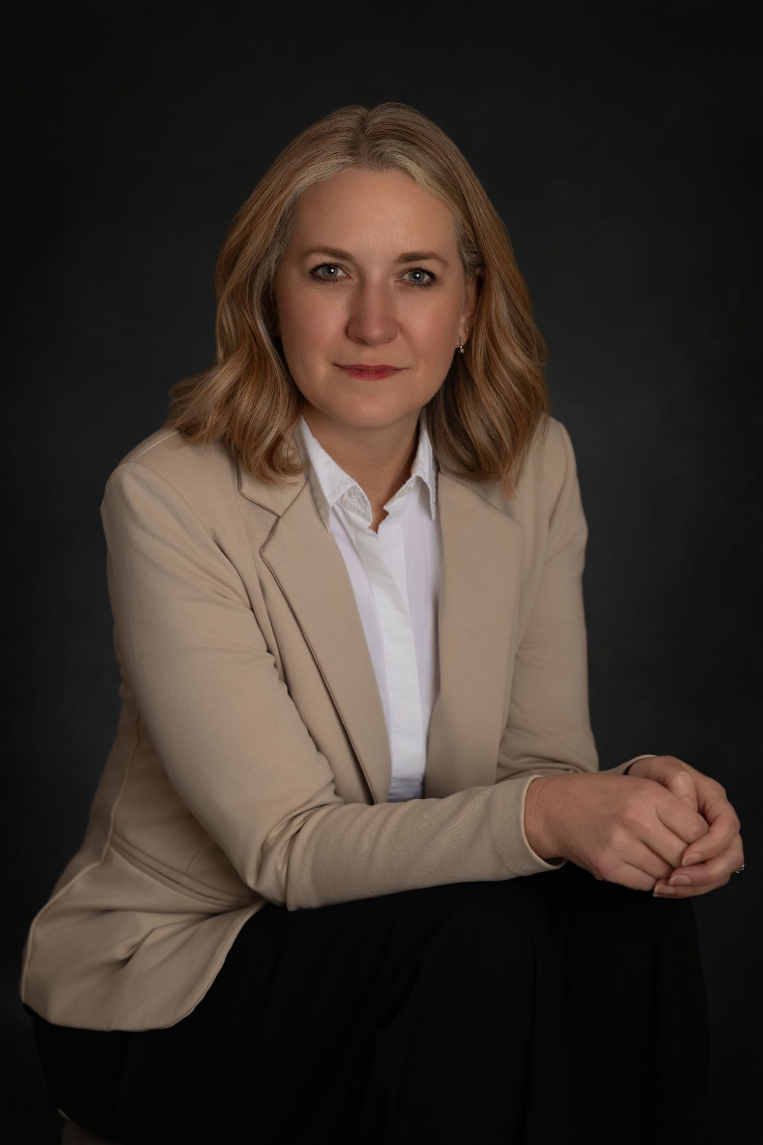Professional headshots against dark background showing person in beige blazer and white shirt in various poses.