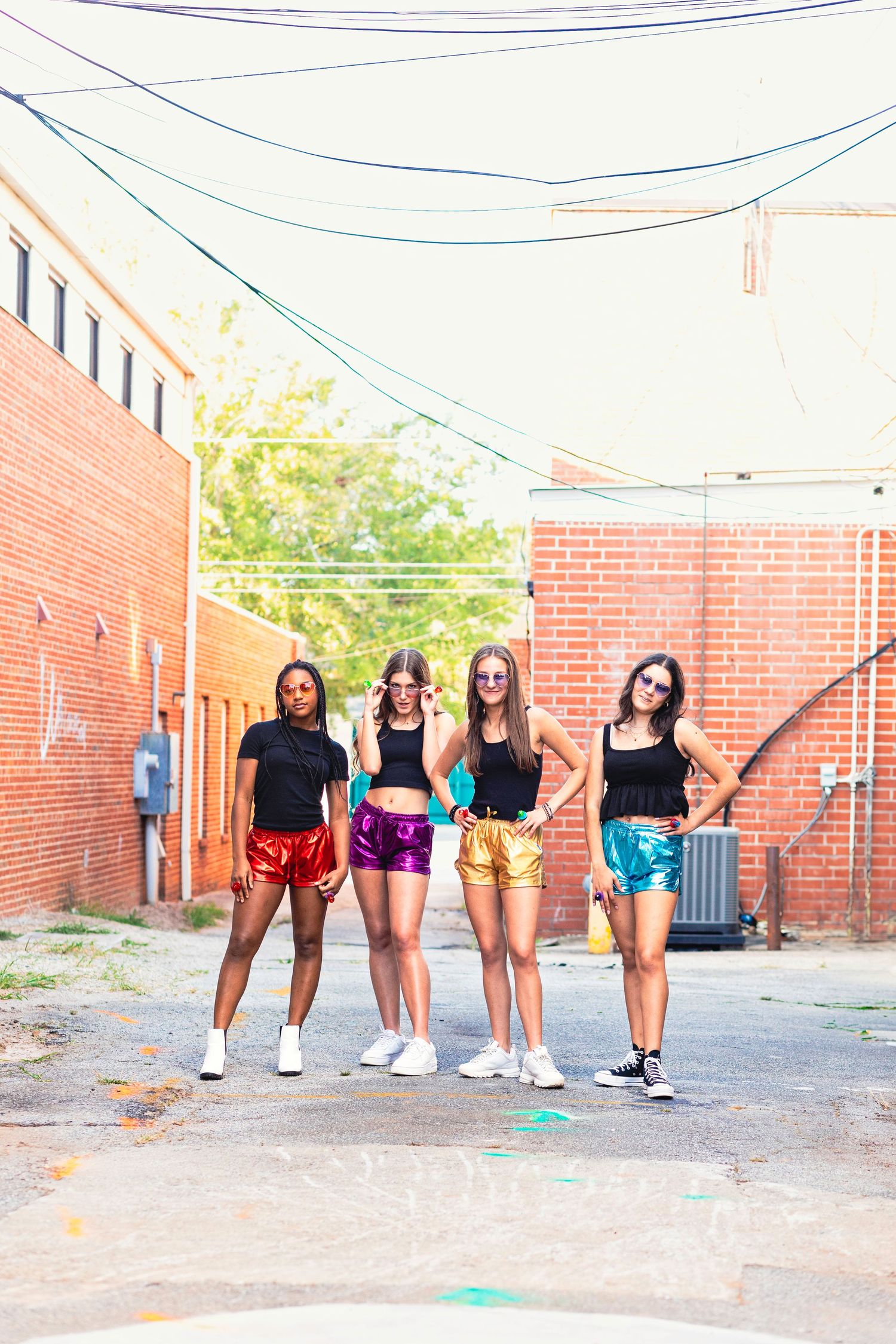 A group in colorful athletic shorts poses together in a line against a brick wall outdoors.