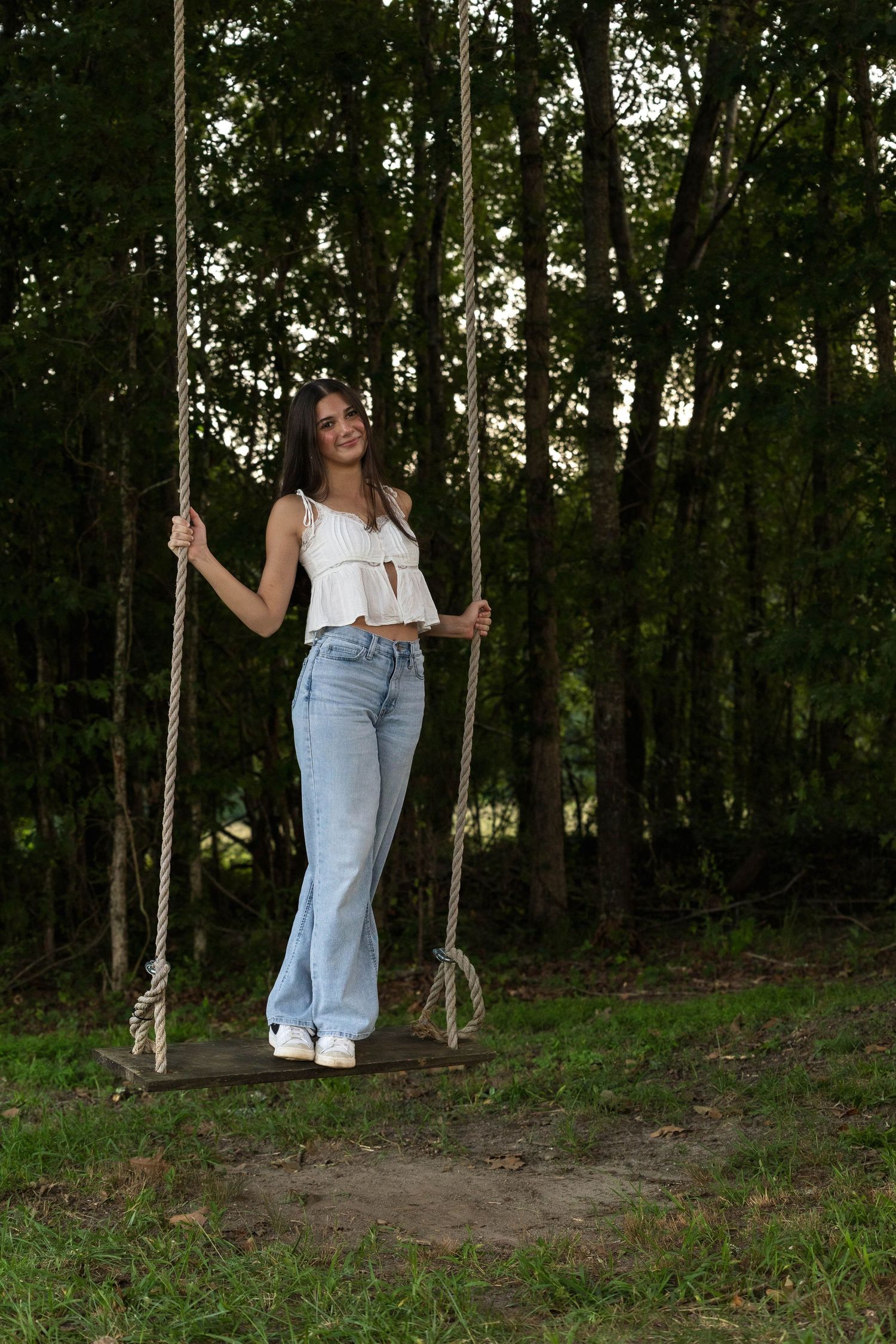 Dreamy forest swing photography session with natural lighting through trees.