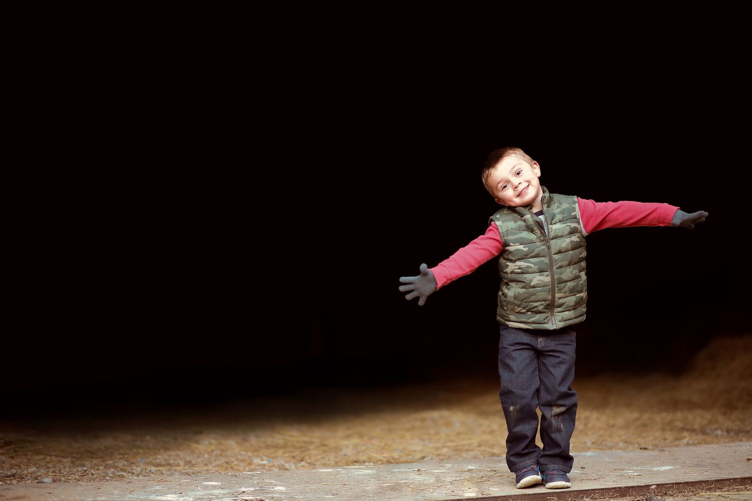 Child striking playful poses against a black background in casual winter clothing.