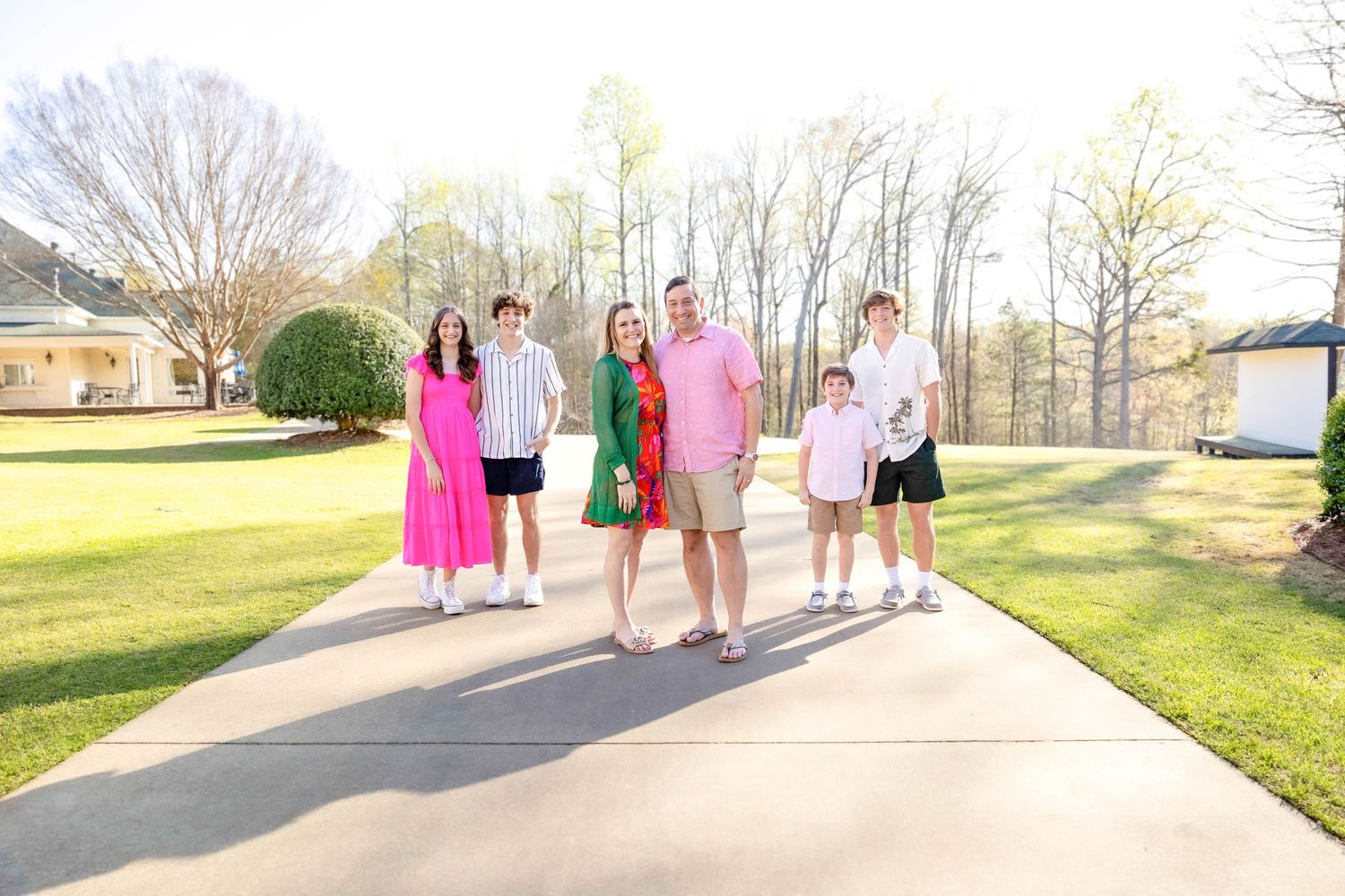 Group walking together on paved path wearing colorful dresses in spring setting.