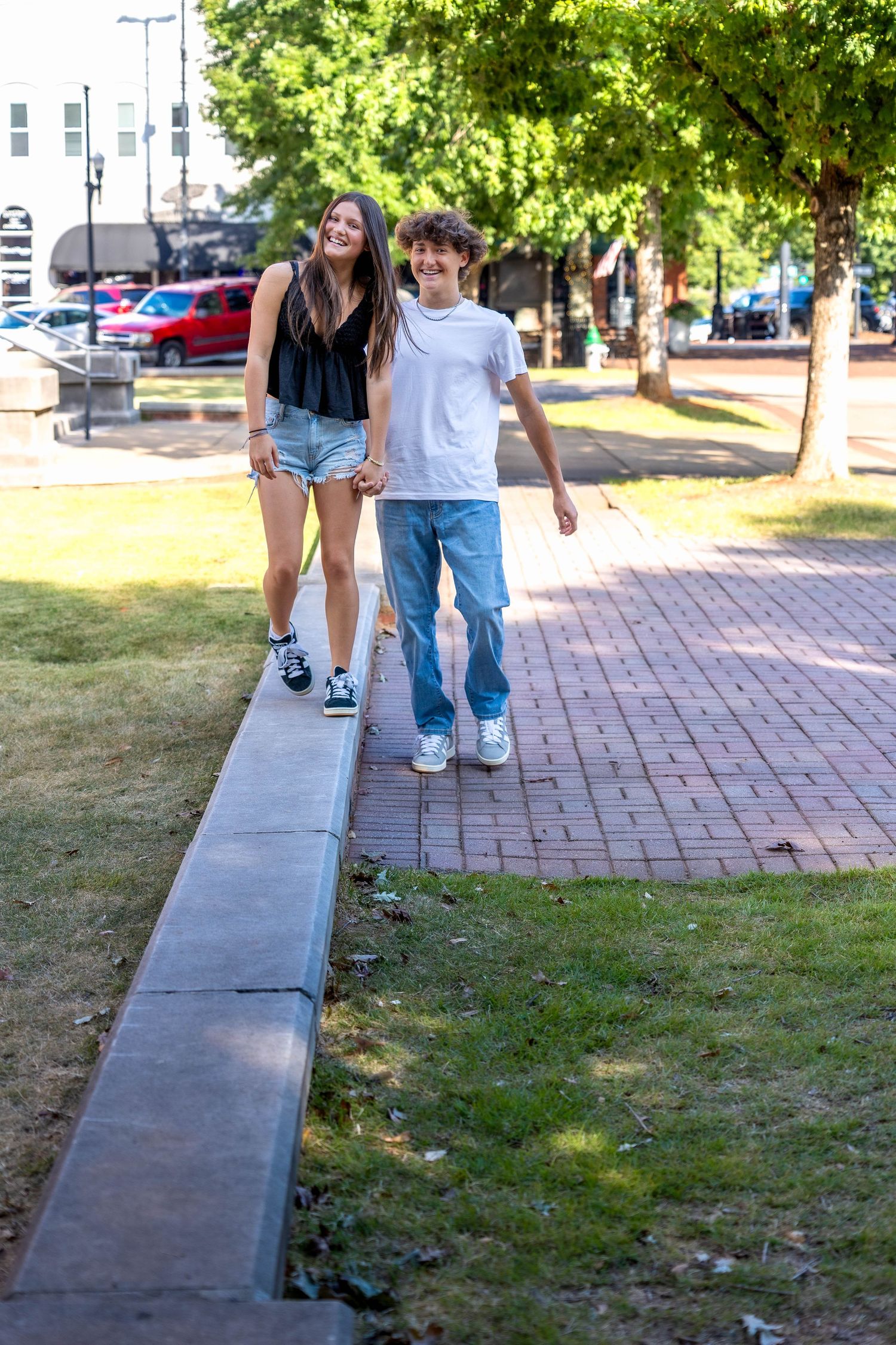People walking along a brick pathway next to a grassy area on a sunny summer day.
