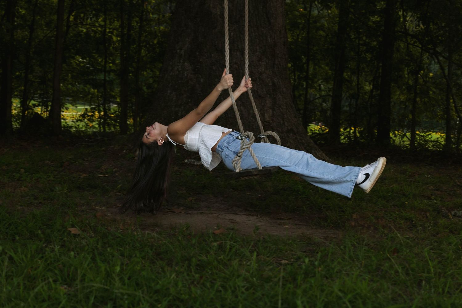 Playful outdoor swing photography in a wooded natural setting.