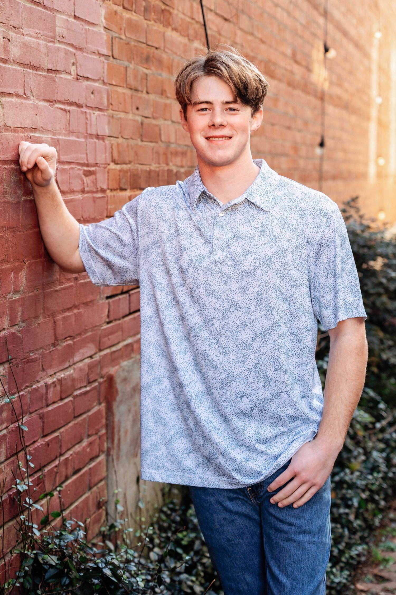 Casual portraits against red brick wall with ivy and greenery.