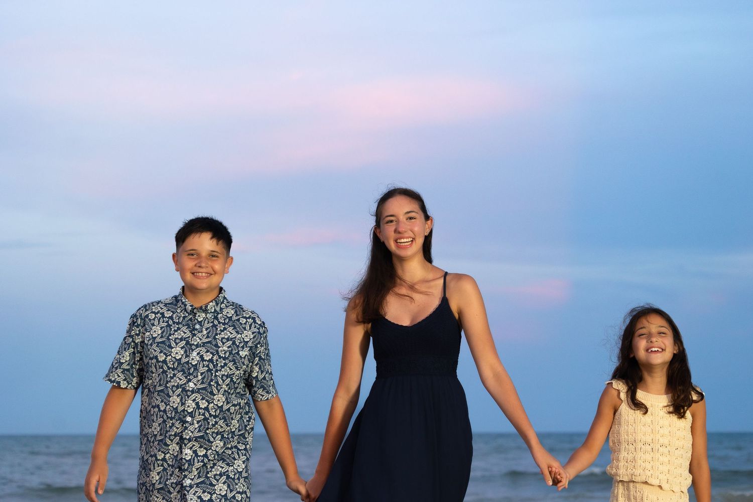 Family standing together on beach at sunset with ocean in background.