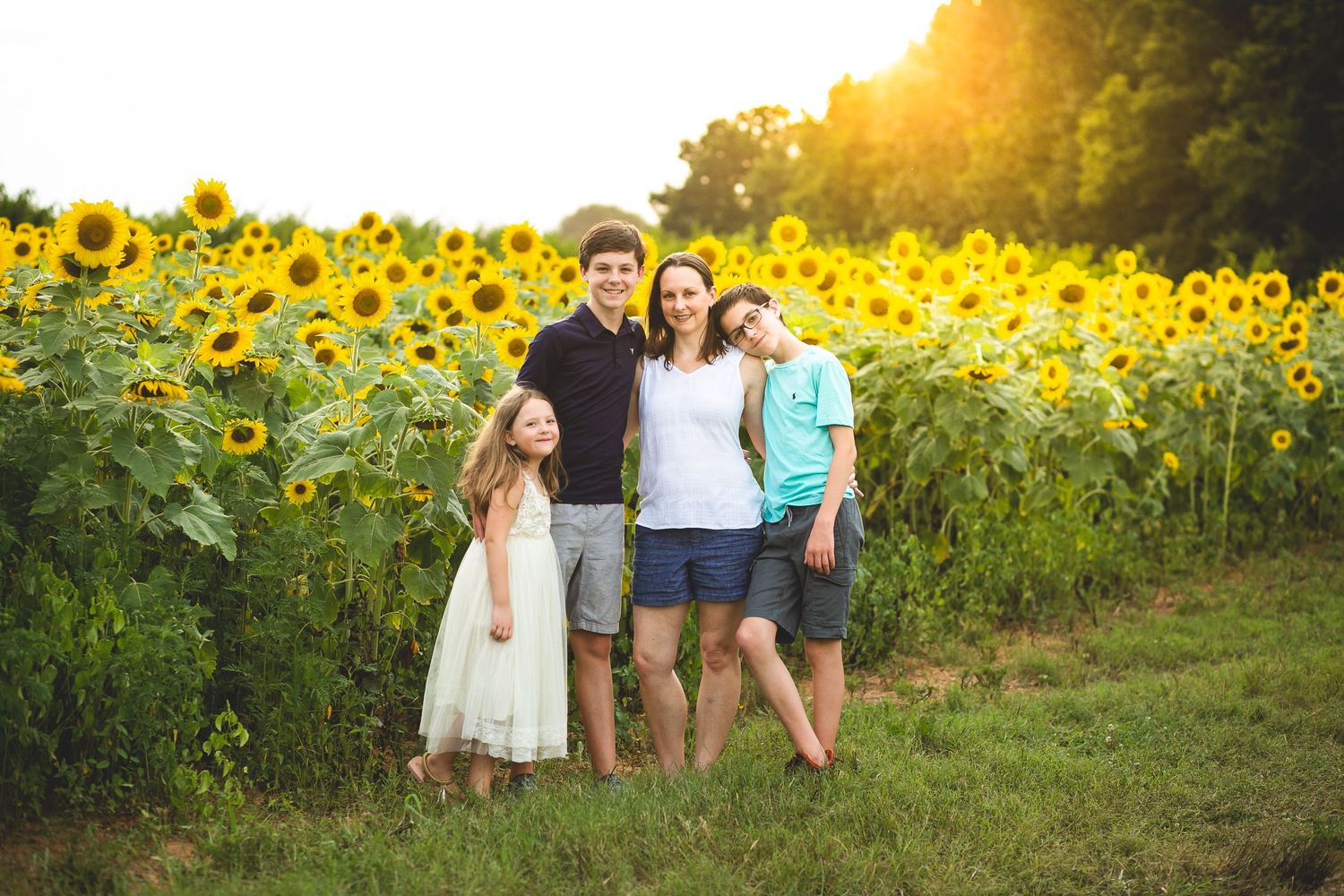 Beautiful family portraits taken in a vibrant sunflower field at sunset.