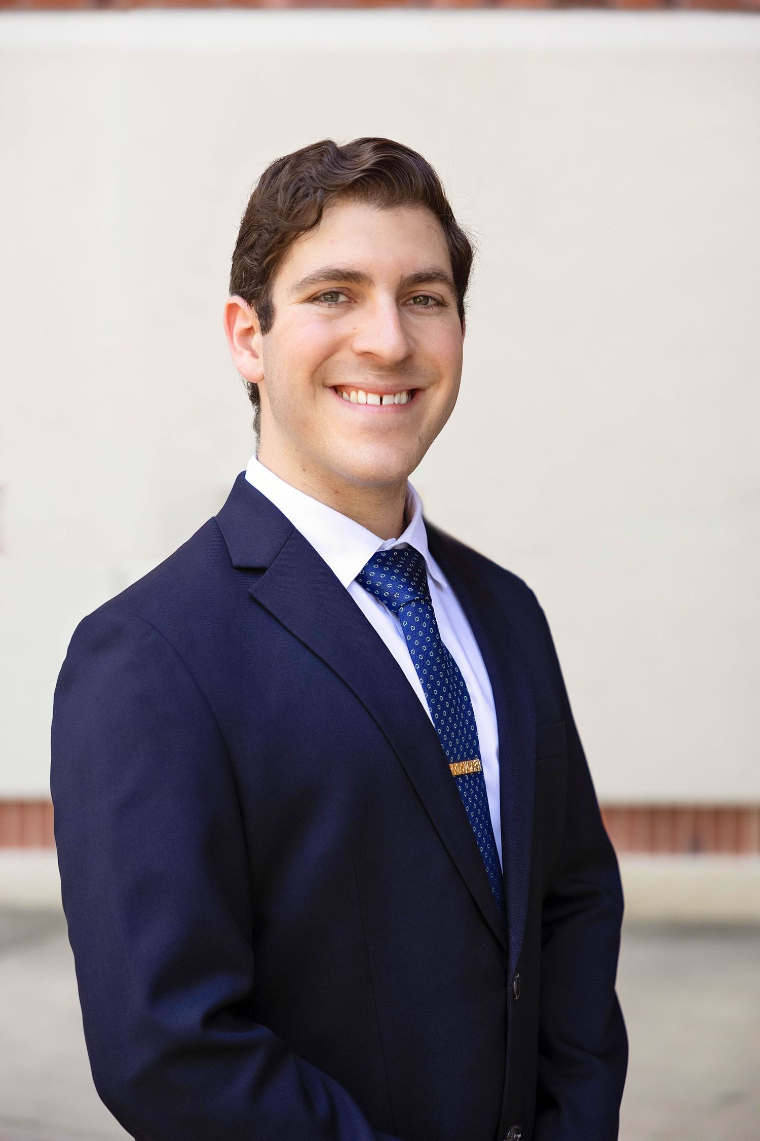 Professional headshot series of person in navy suit and polka dot tie against light background.