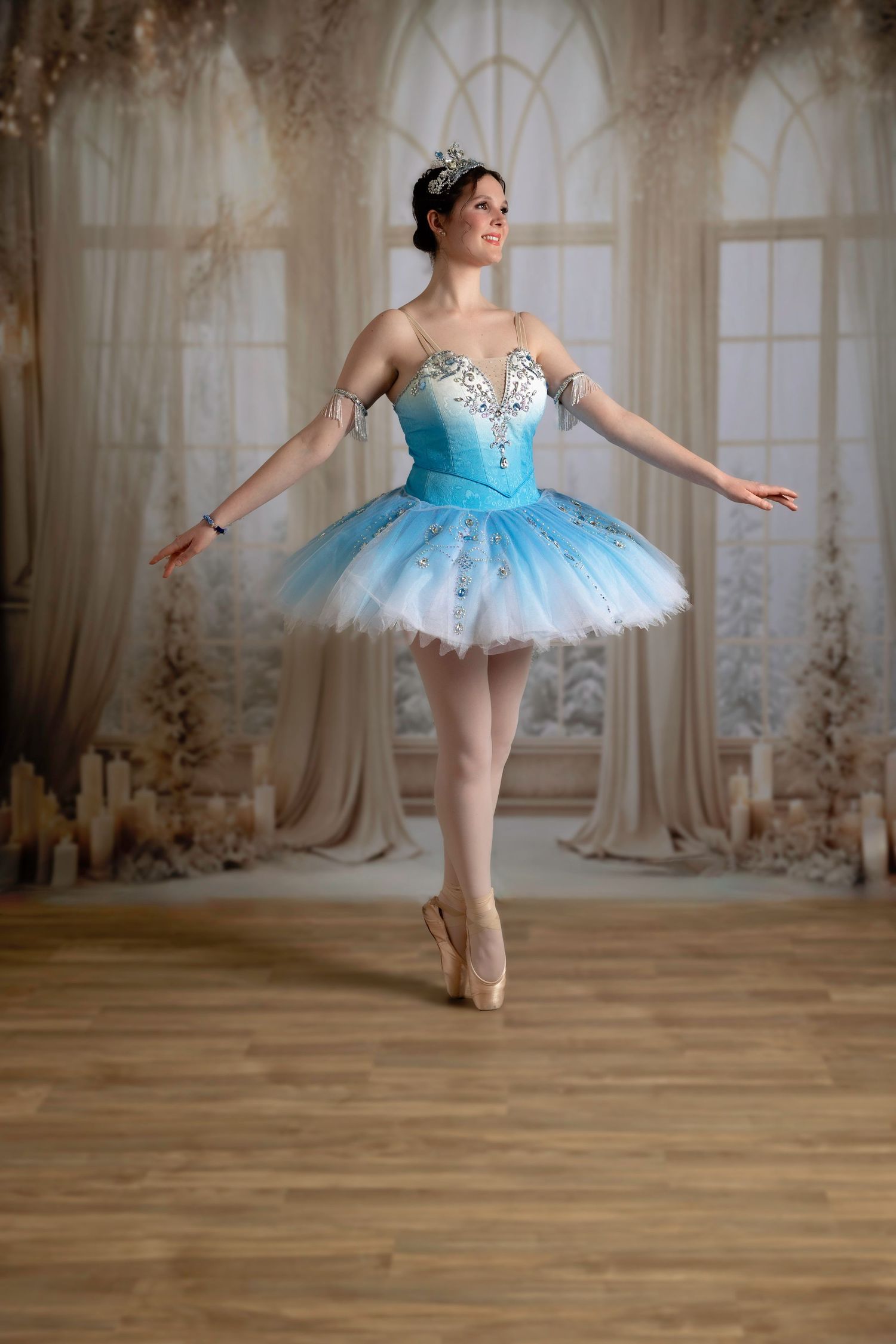 Dancer in light blue tutu performs ballet movements in an elegant interior setting.