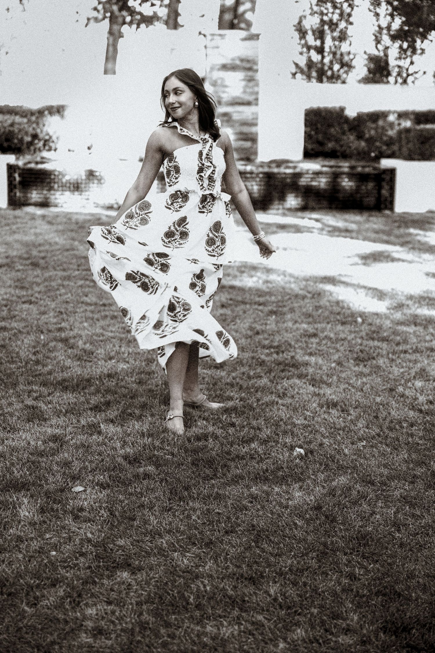 A series of black and white photos showing a flowing white dress twirling on a grassy lawn.