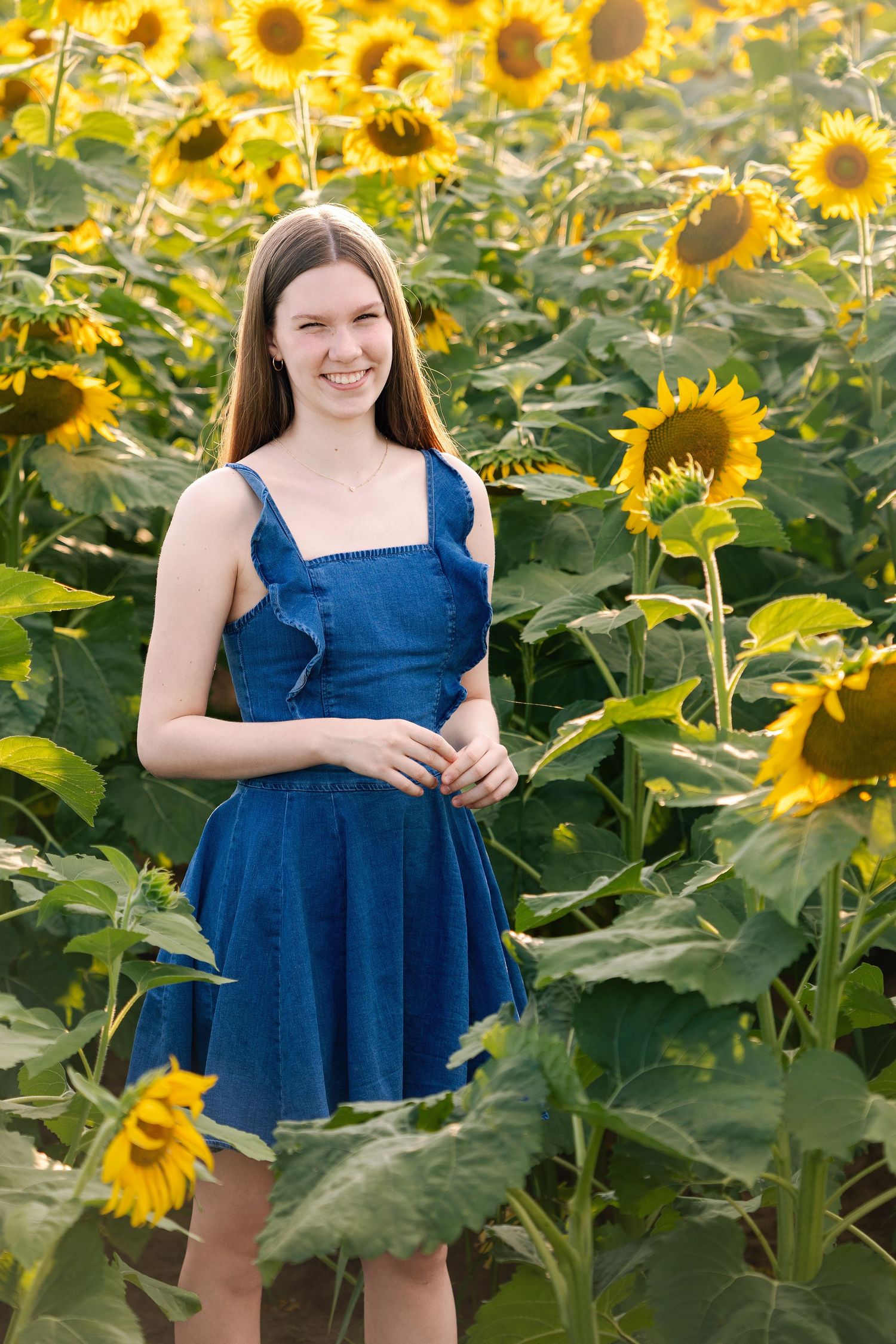 Vibrant sunflower field with blue dress contrasting against yellow blooms.
