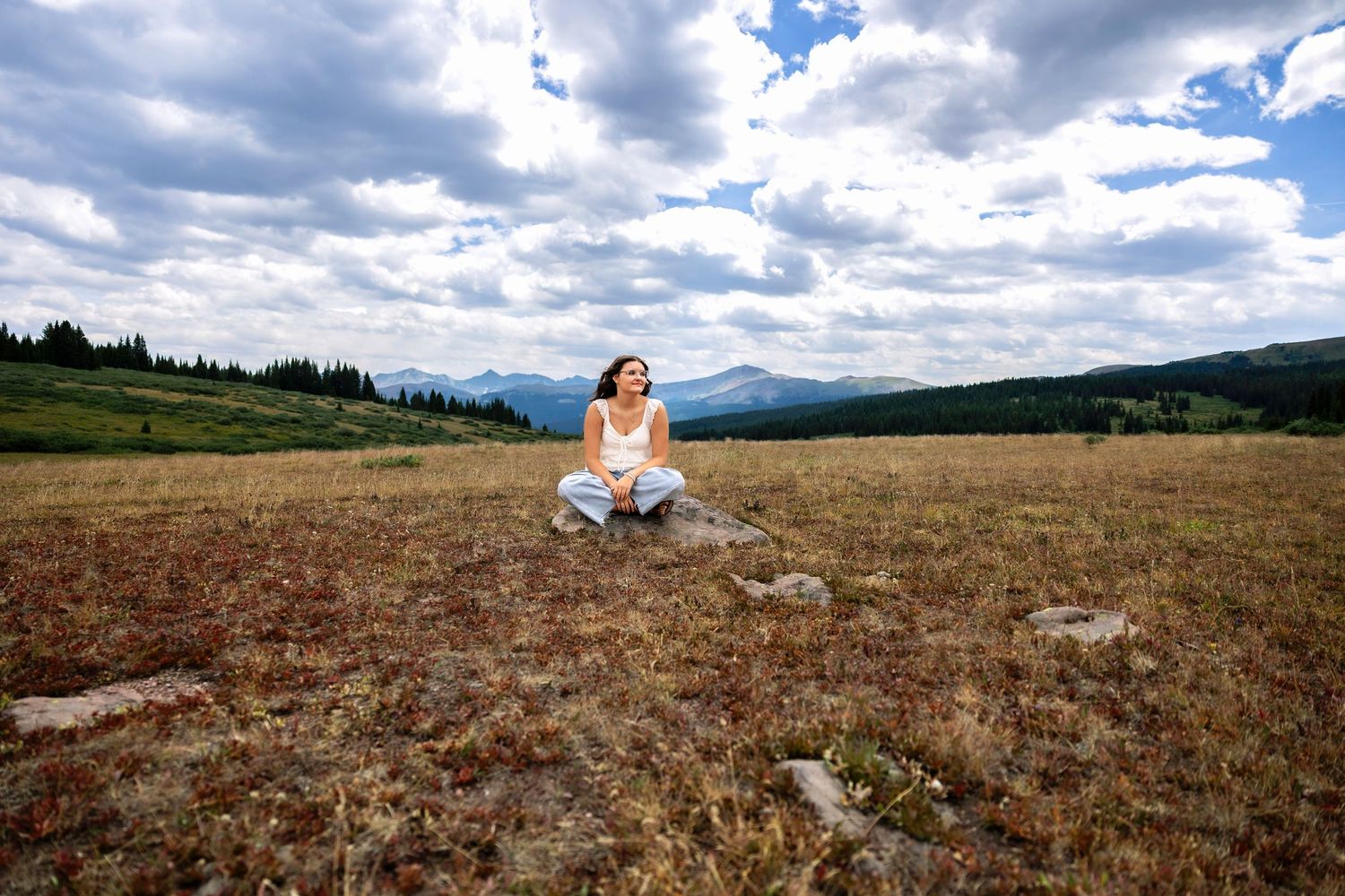Panoramic mountain landscape with cloudy skies and rolling hills covered in dry grass.