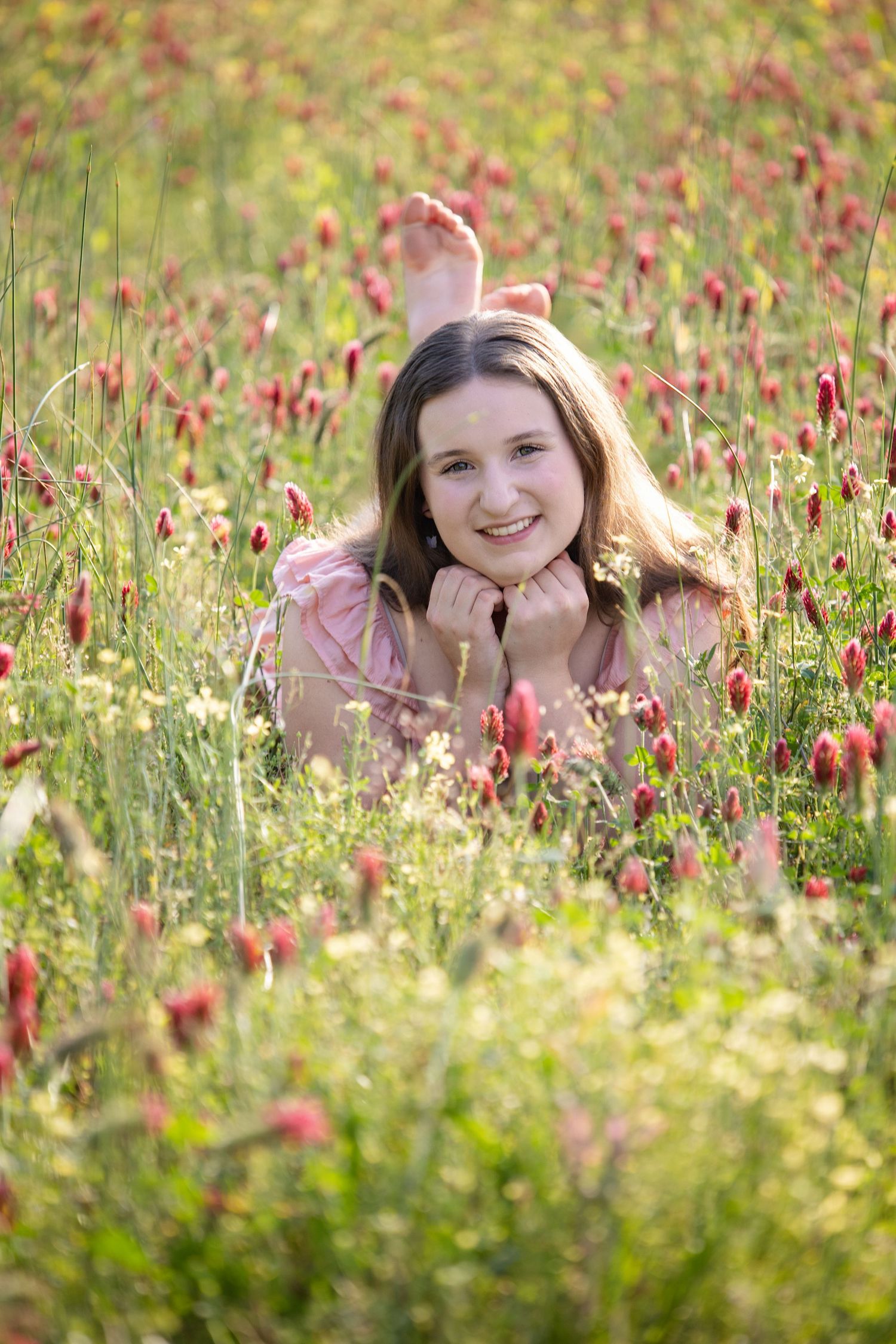 Spring portrait in field of red crimson clover flowers with soft natural lighting.