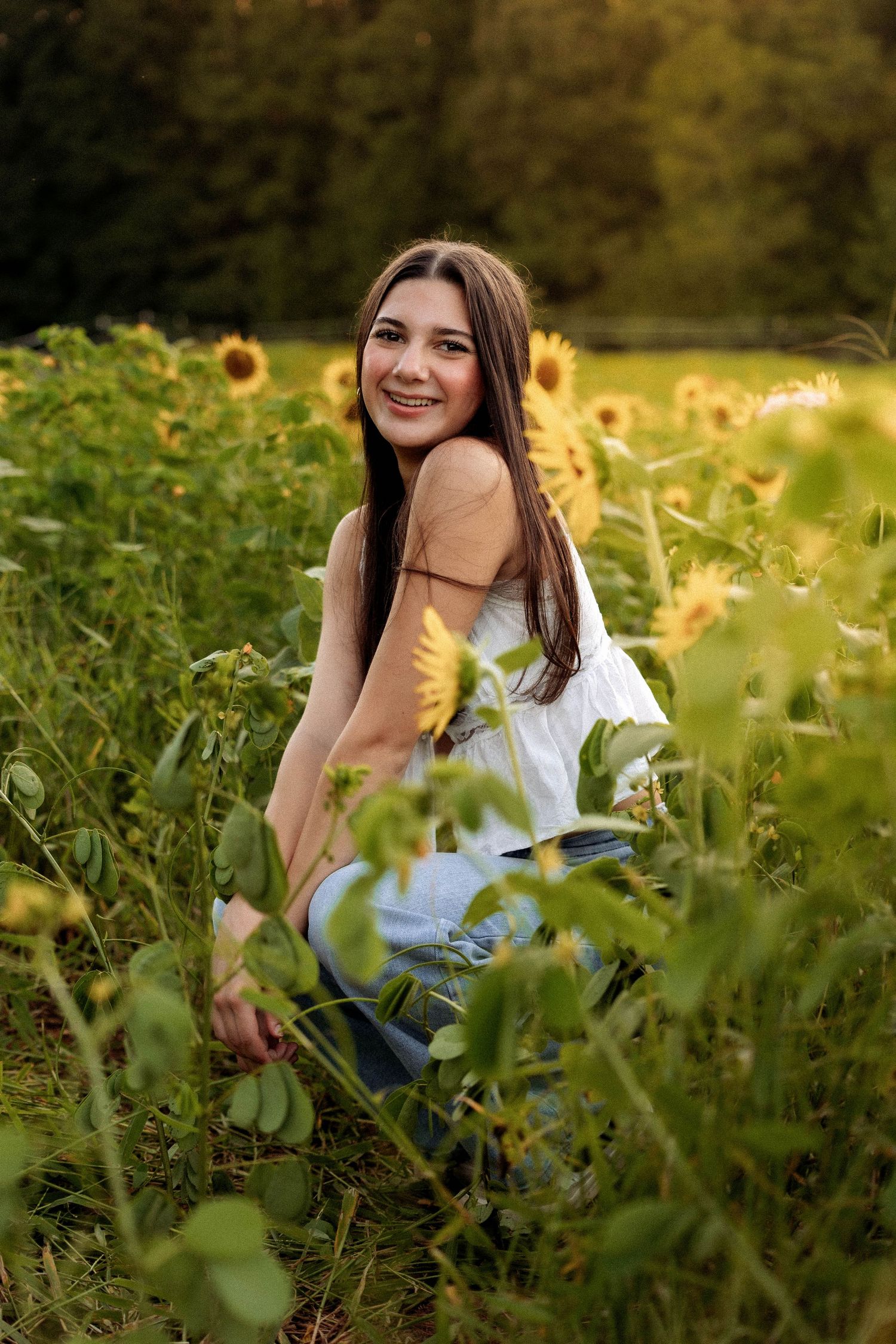Person in casual attire surrounded by vibrant sunflowers during a summer photoshoot.