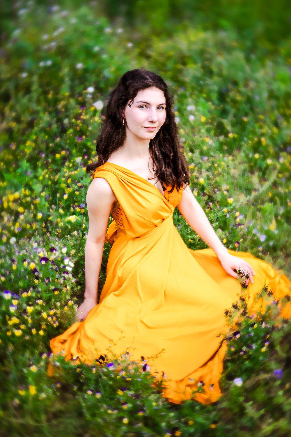 Woman in flowing yellow dress twirls gracefully among wildflowers in a meadow.