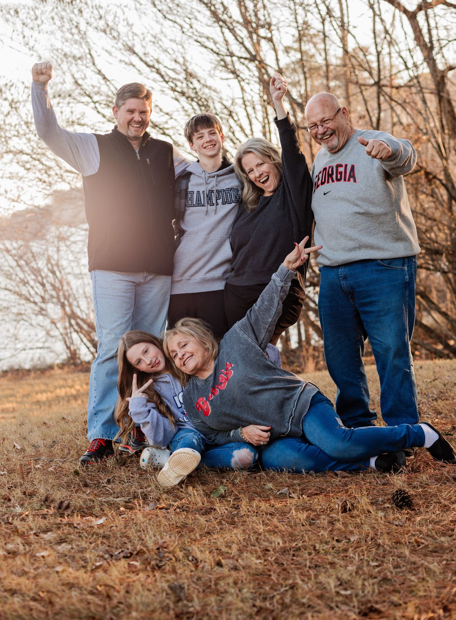 Casual family photo session with everyone sitting on fallen autumn leaves.