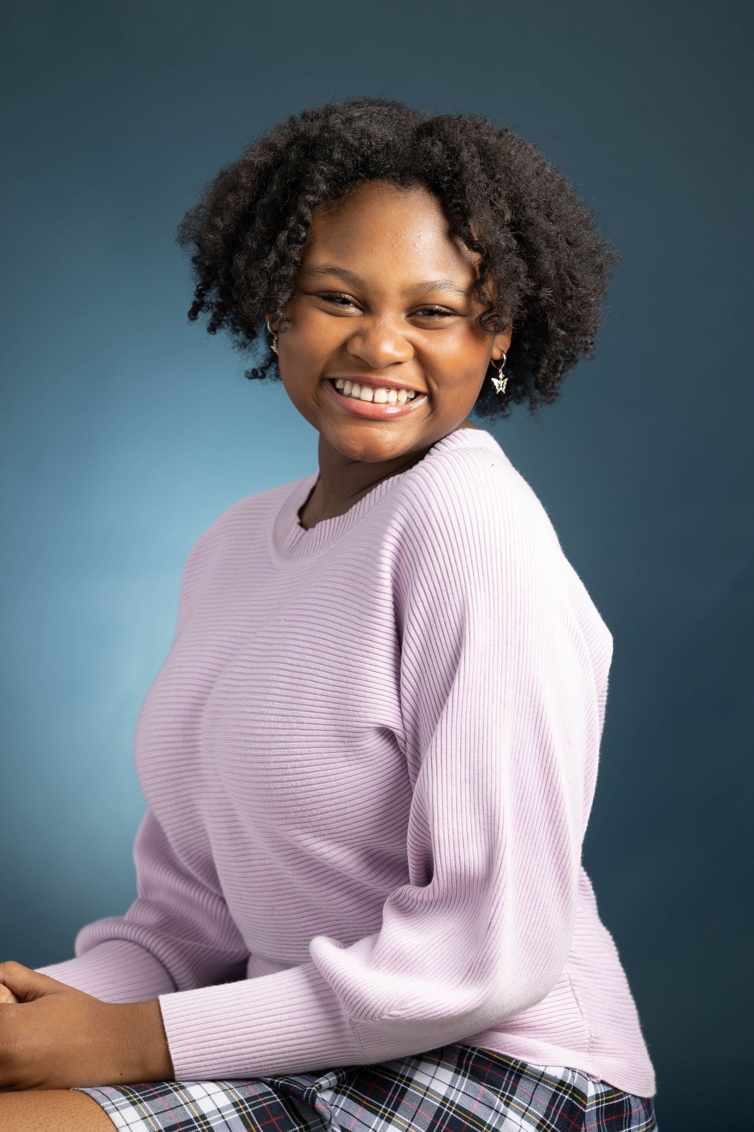 Studio portrait series featuring person in lavender sweater against blue backdrop.