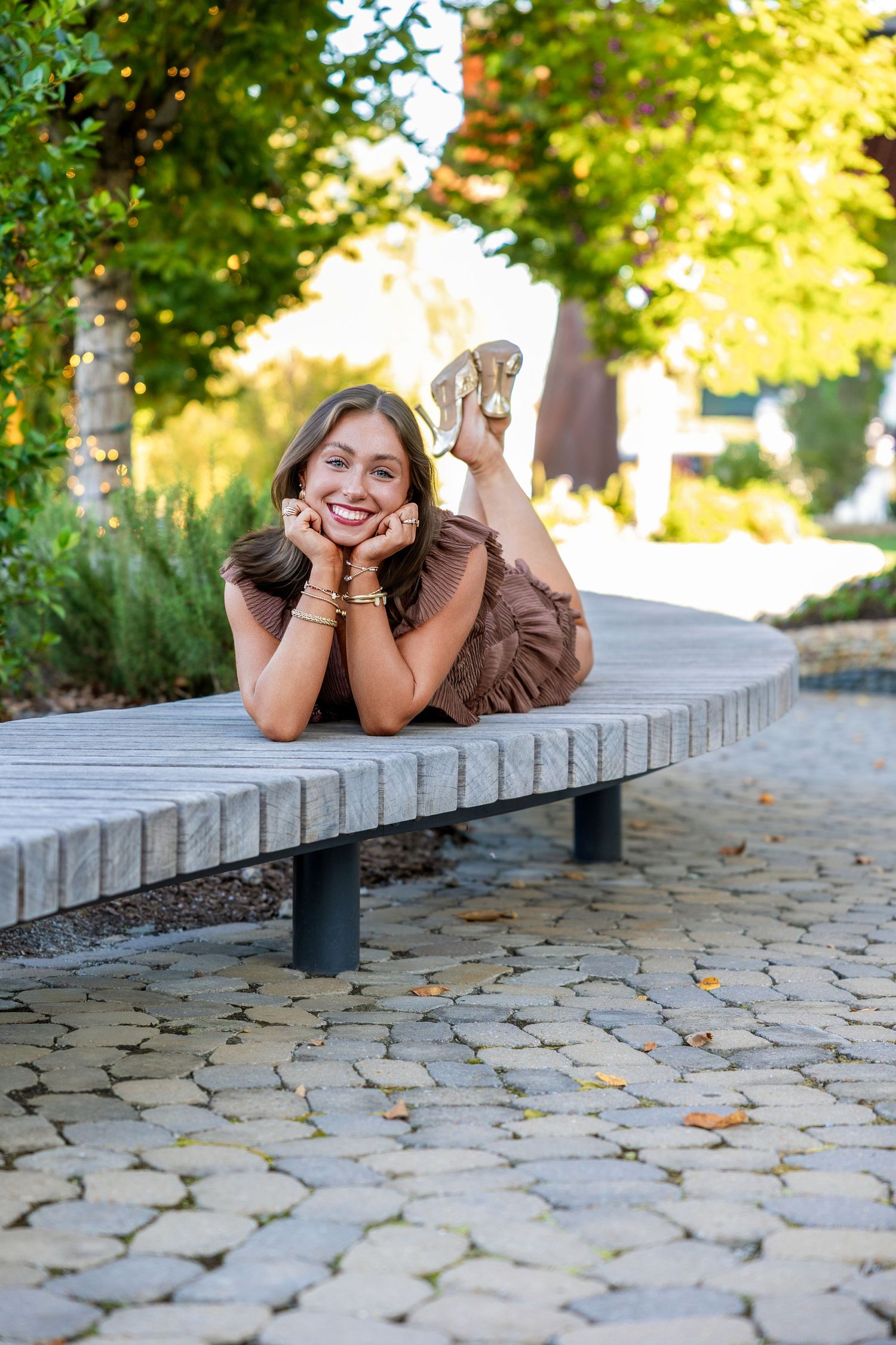 A sequence of playful poses on a stone paved walkway surrounded by greenery in warm sunlight.
