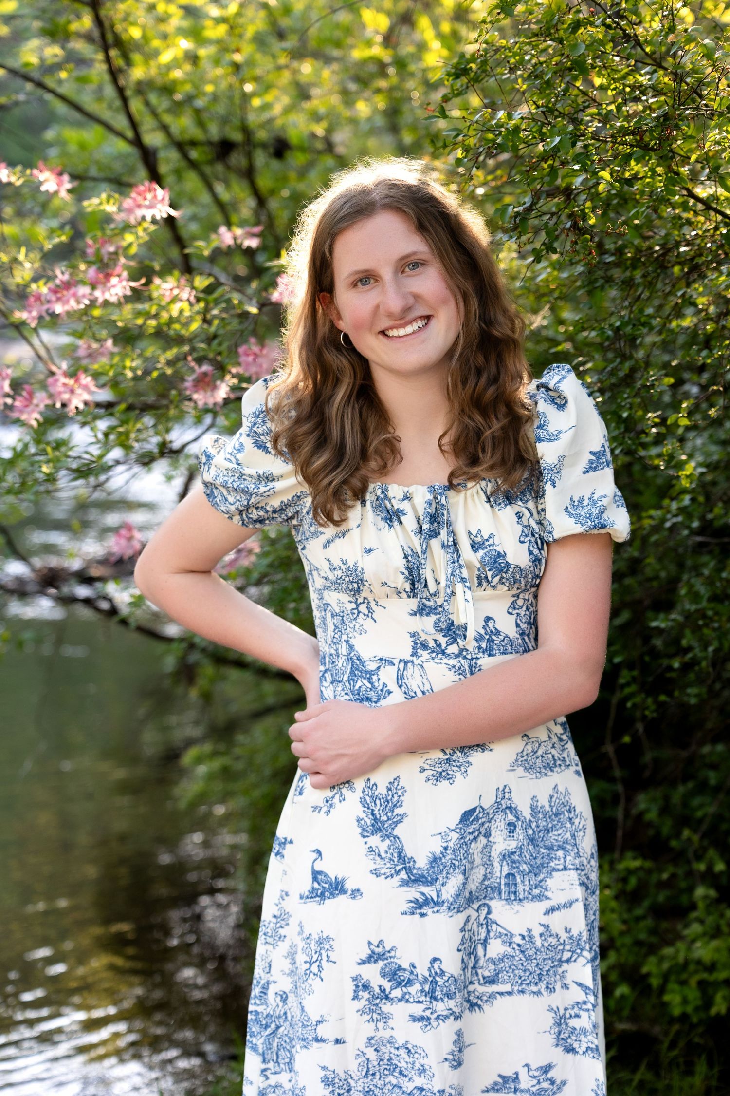 A series of outdoor portrait photos featuring someone in a blue and white floral dress posing by a lake in nature.