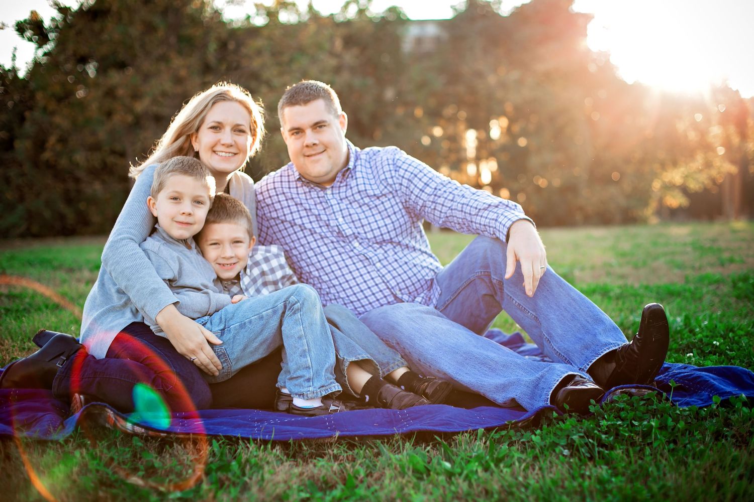 Family lounging together on green grass during golden hour sunset photoshoot.