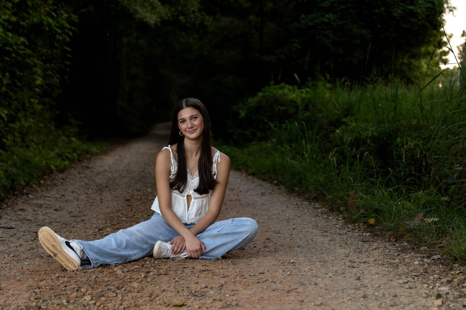 Casual outdoor portrait session on a rustic dirt path surrounded by greenery.