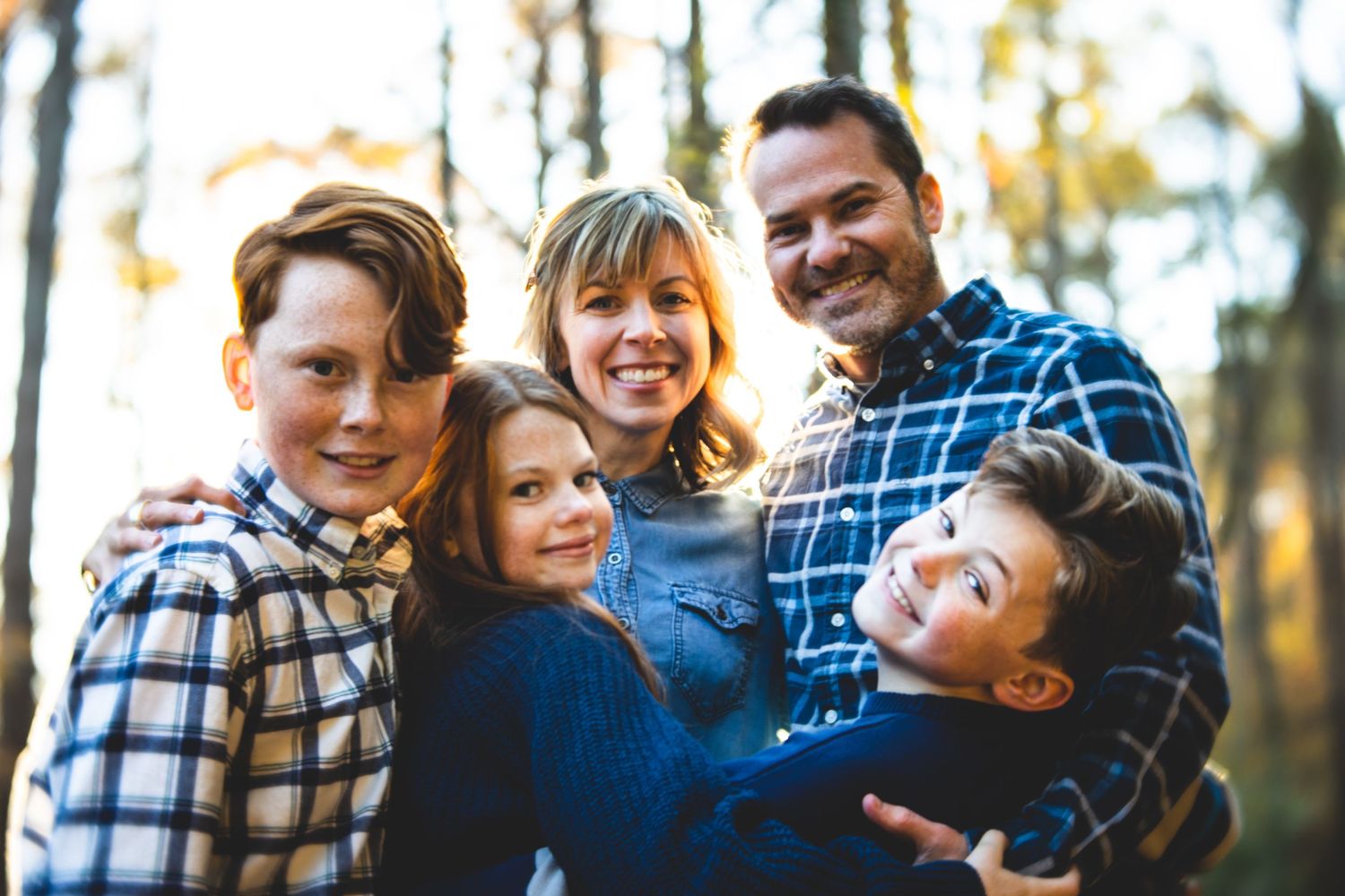 Family wearing coordinated blue plaid outfits during autumn photo session.