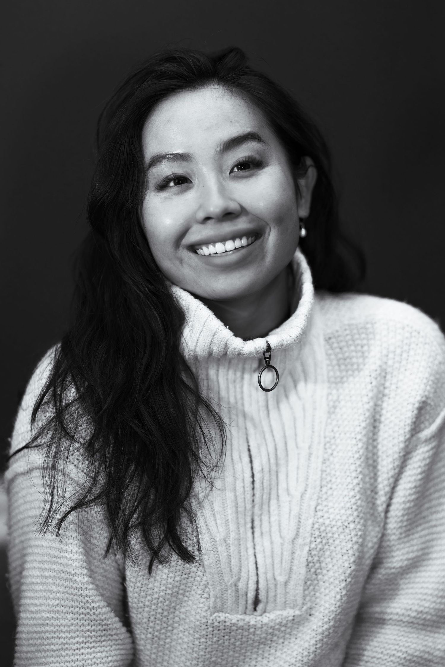 Portrait of the photographer, Mai Dang in a white knit sweater.
