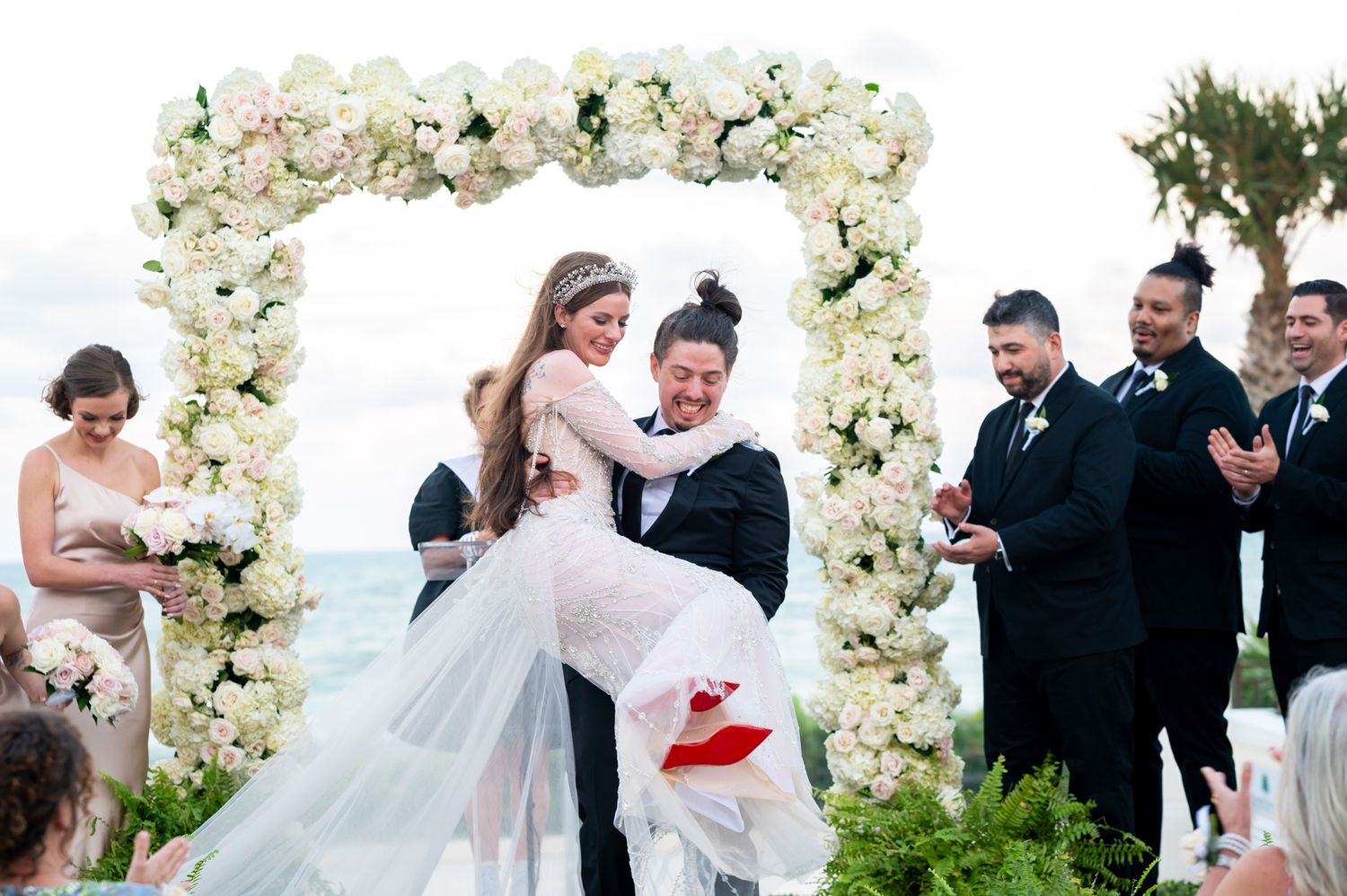 The groom picks up his bride at the altar during their luxury beach wedding, photographed by a Palm Beach wedding photographer.