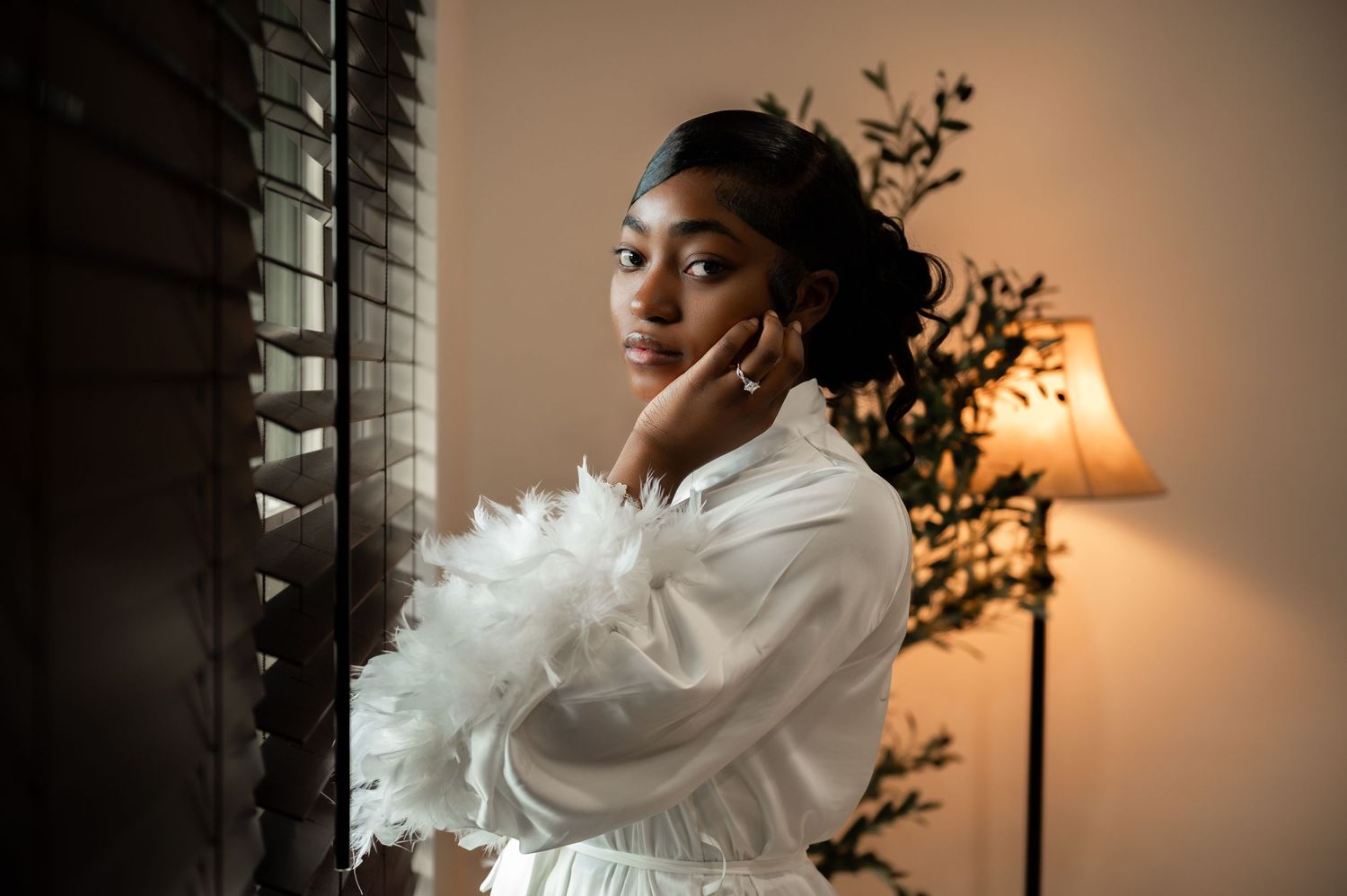 Beautiful soft light touches the bride's face as she stands by the window captured by South Florida wedding photographers.