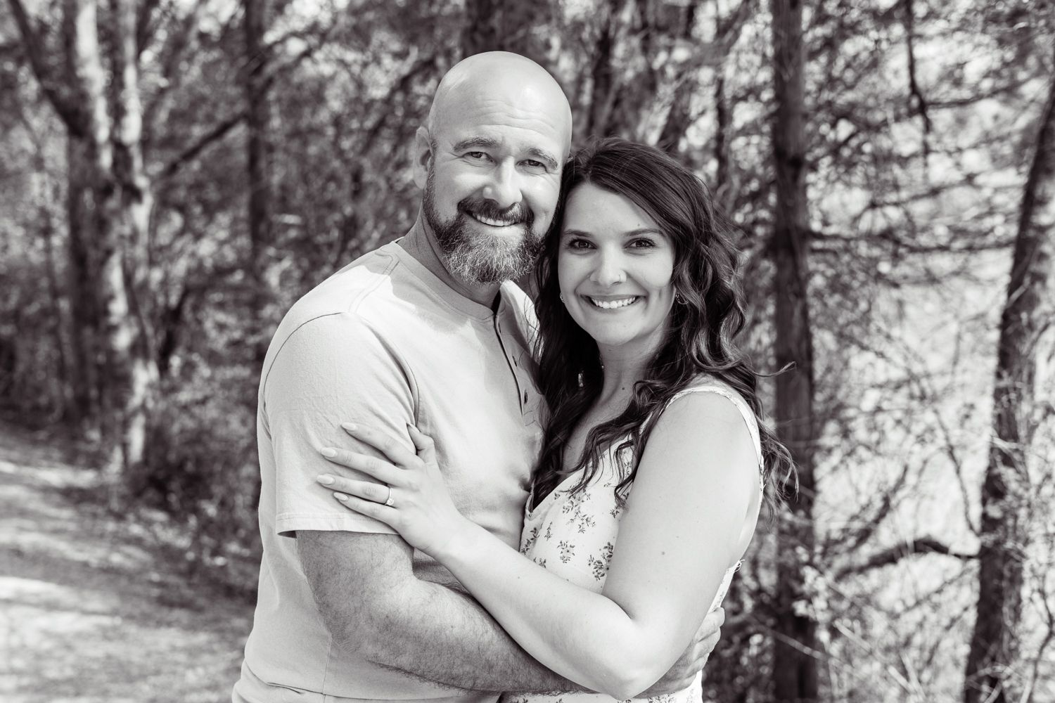 Candid black and white photograph of a smiling couple during their engagement photo shoot, capturing a natural, joyful moment between them.