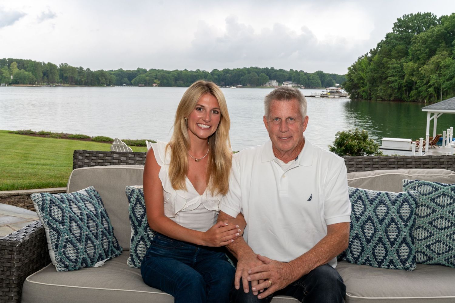 A beautifully lit, candid portrait of a father and his daughter smiling together with a beautiful lake in the background.