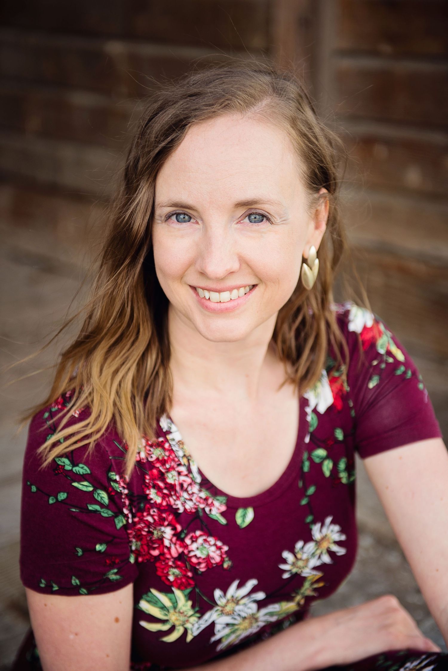 A person in a burgundy floral dress poses for a series of professional headshots with a warm smile.
