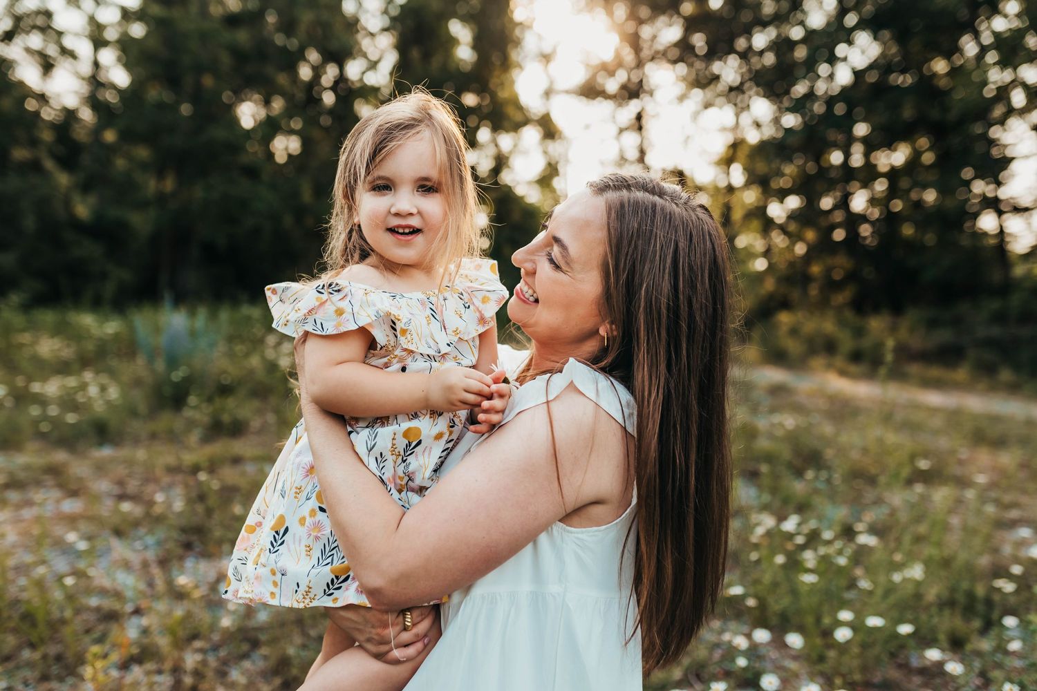 Candid lifestyle portrait of parent and child laughing together in natural outdoor setting.