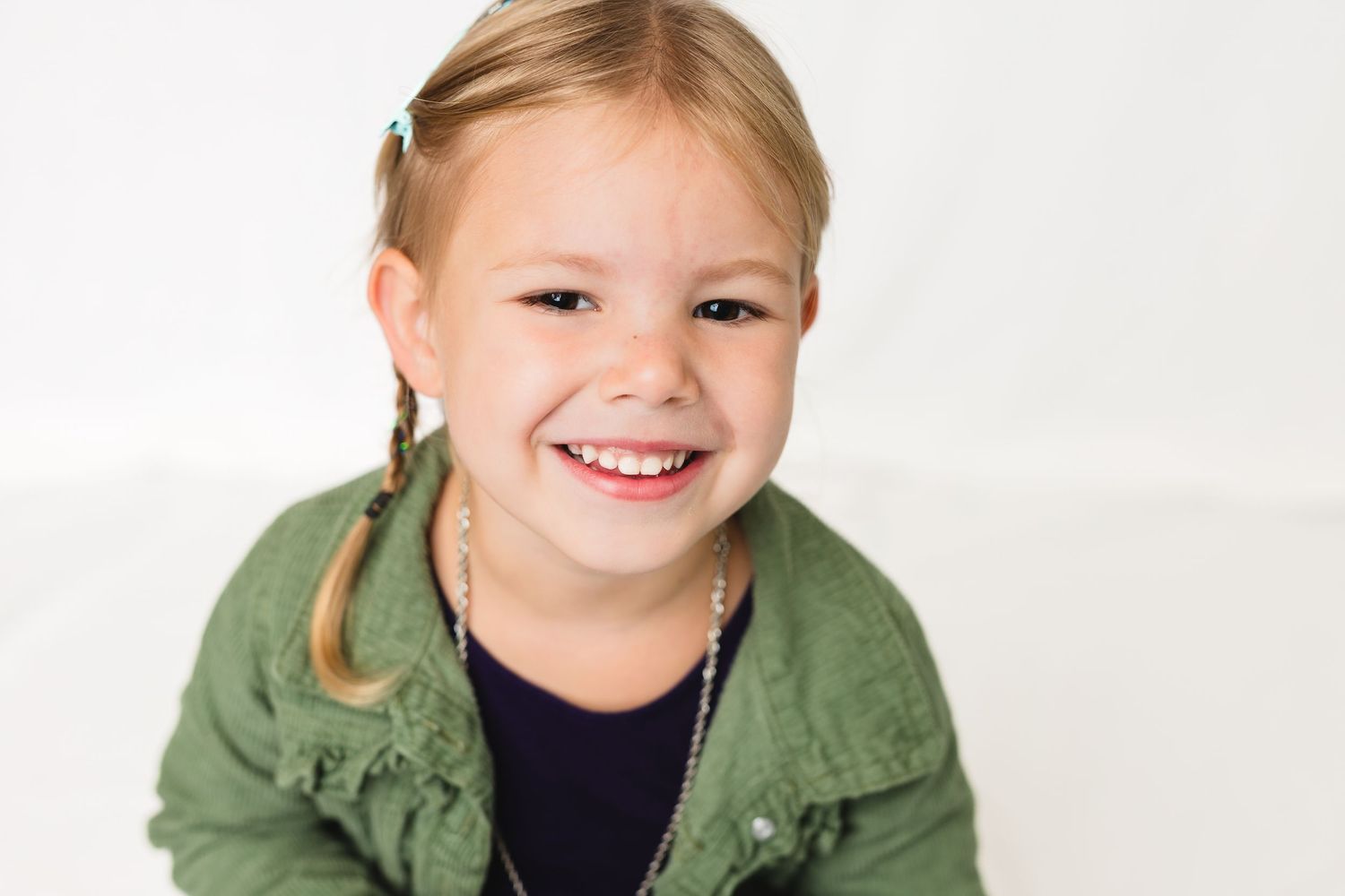 Happy young individual in a green jacket against a clean white background with three expressive poses in a row.