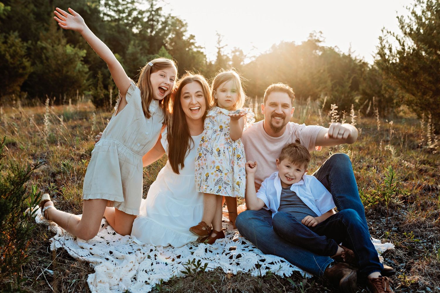 Happy family with kids posing playfully during sunset outdoor photoshoot.