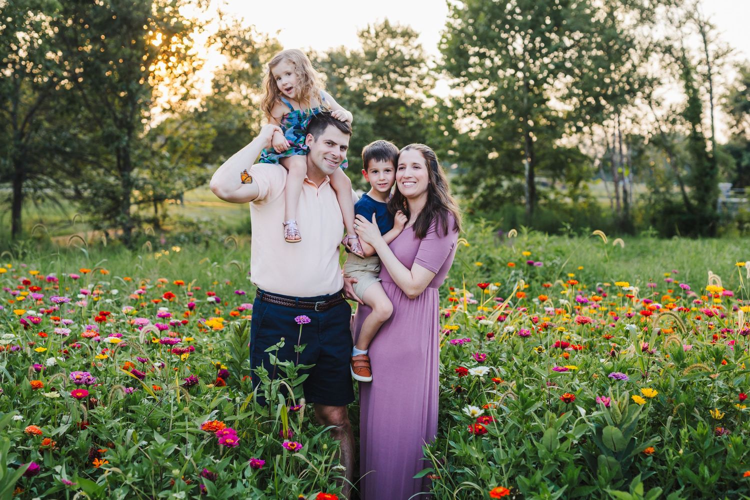Young couple stands together in a vibrant wildflower meadow with red and orange blooms during golden hour.