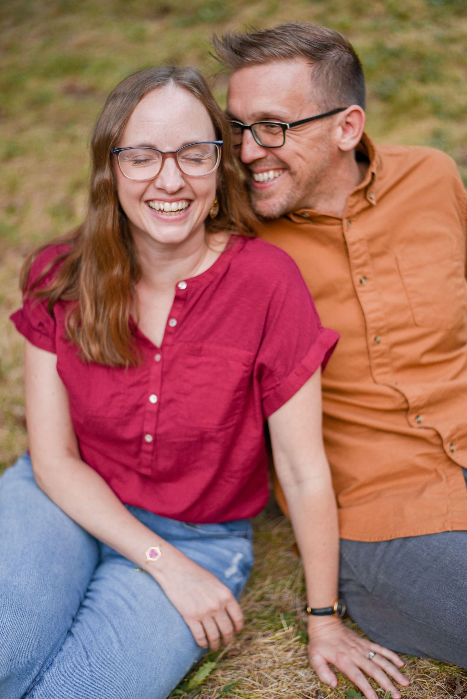 Couple sharing genuine laughter while sitting together outdoors.
