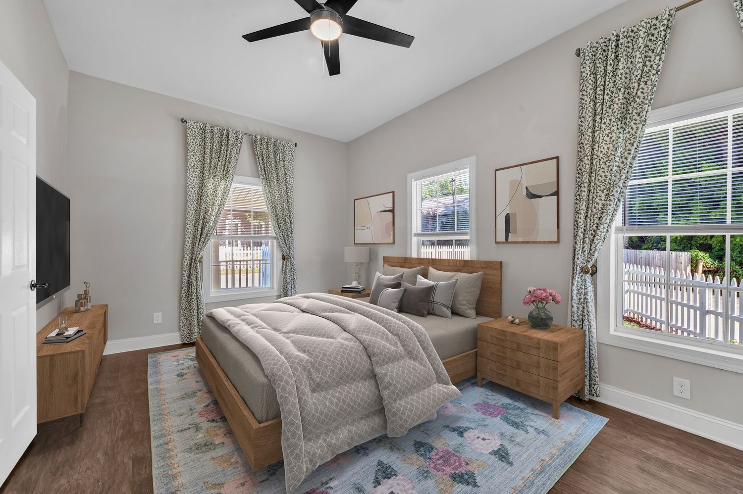 Cozy bedroom with wooden furniture, gray bedding, and floral area rug.